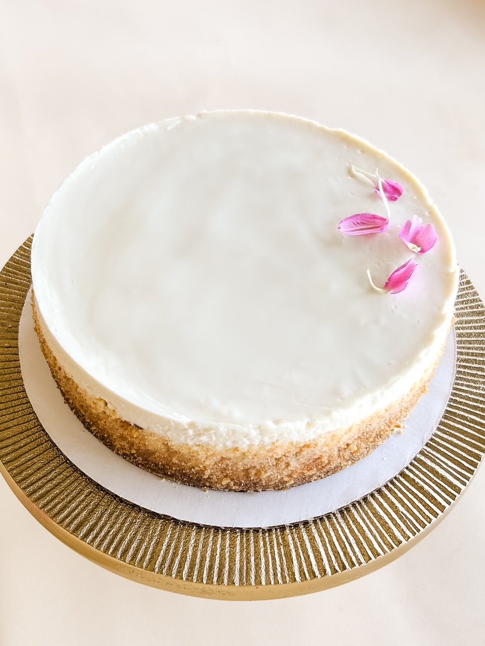 Cheesecake on gold cake pedestal on beige background