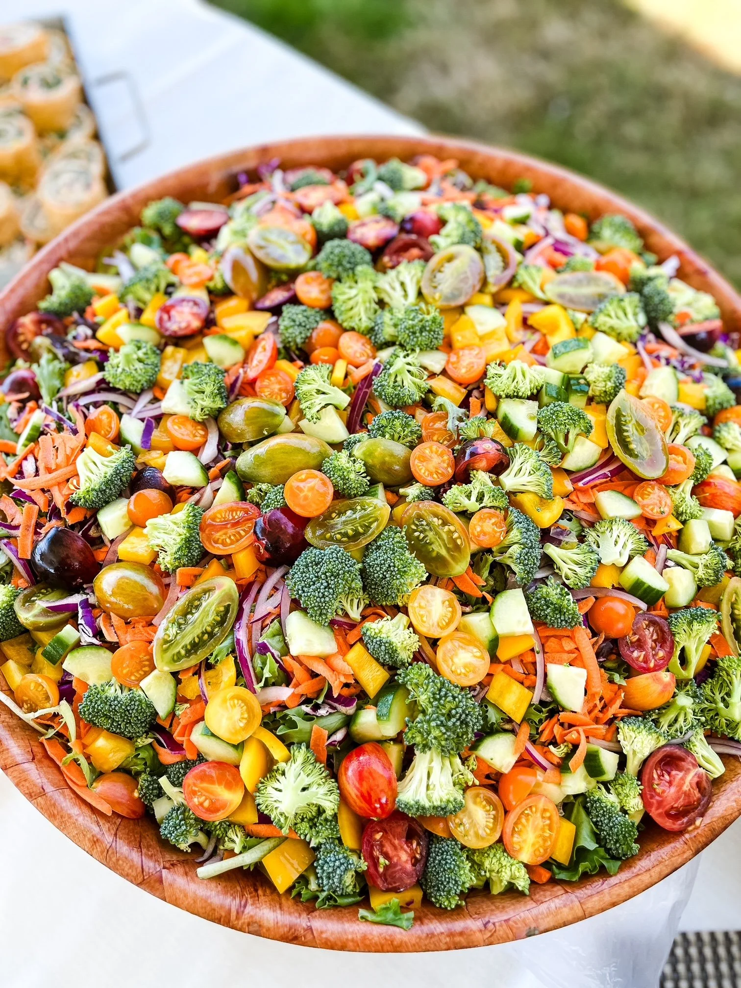 A large wooden bowl filled with a colorful chopped vegetable salad