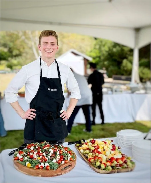Caterer standing in front of caprese skewers tray and fruit skewers tray