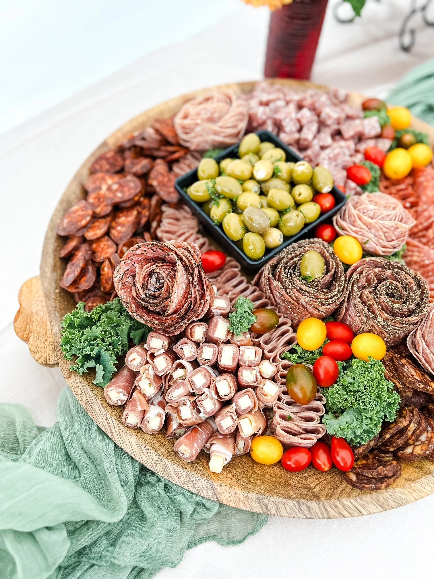 A round wooden platter featuring an assortment of cured meats
