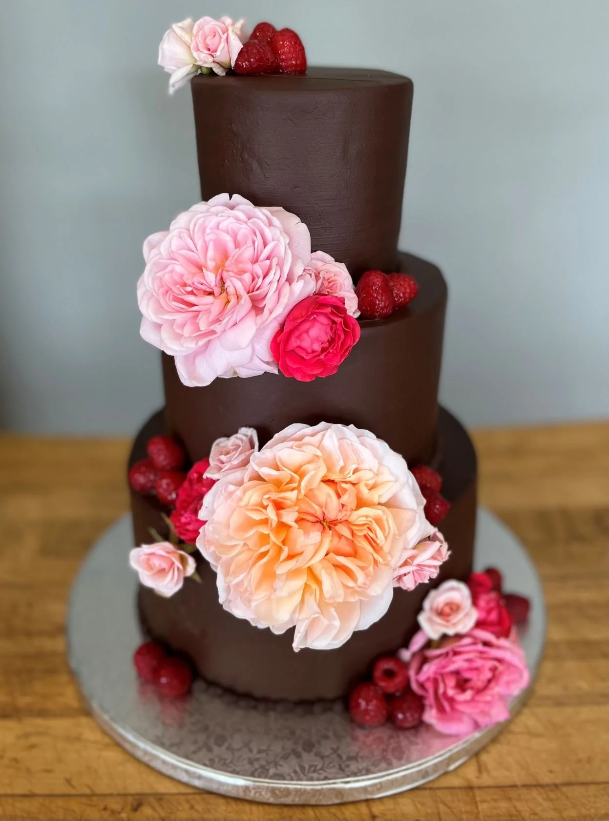 3-tiered chocolate wedding cake decorated with pink and orange roses