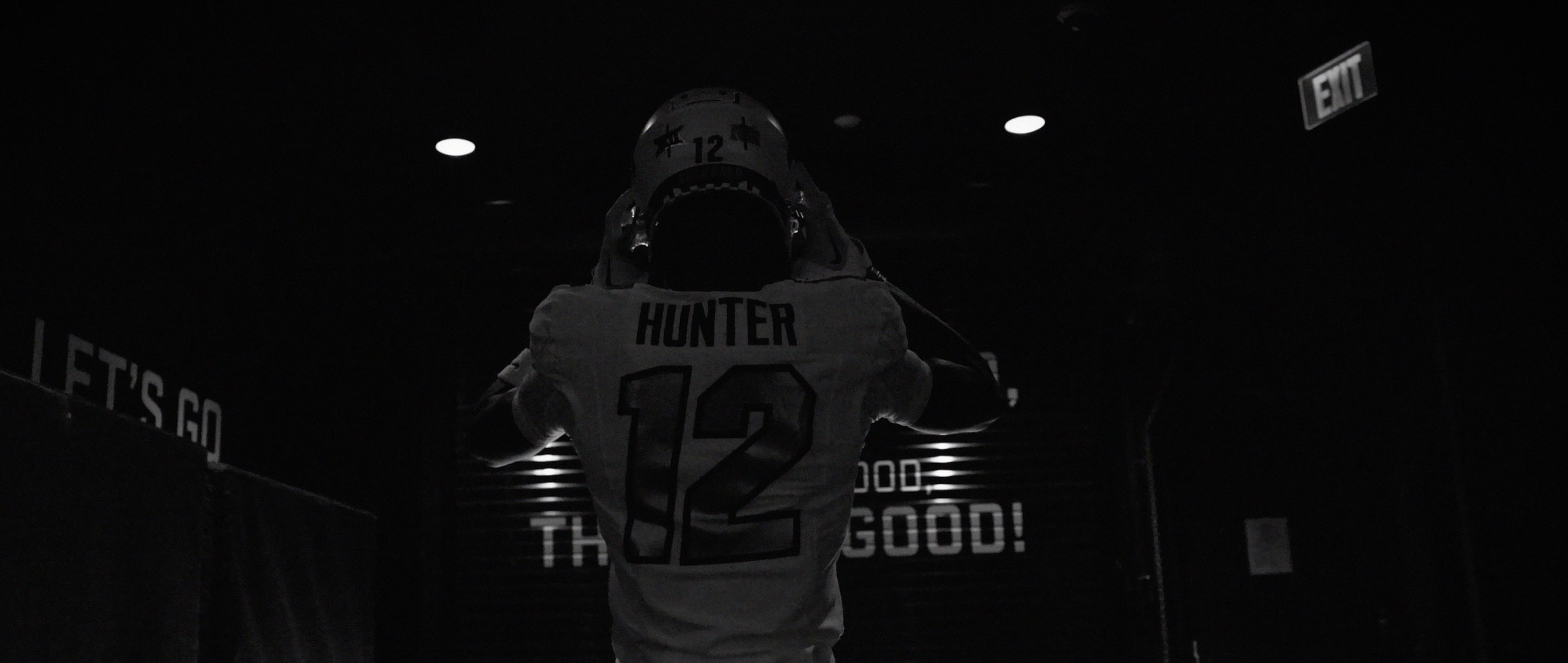 An American football player wearing a helmet and jersey with the name 'Hunter' and number 12, standing in a dark tunnel.
