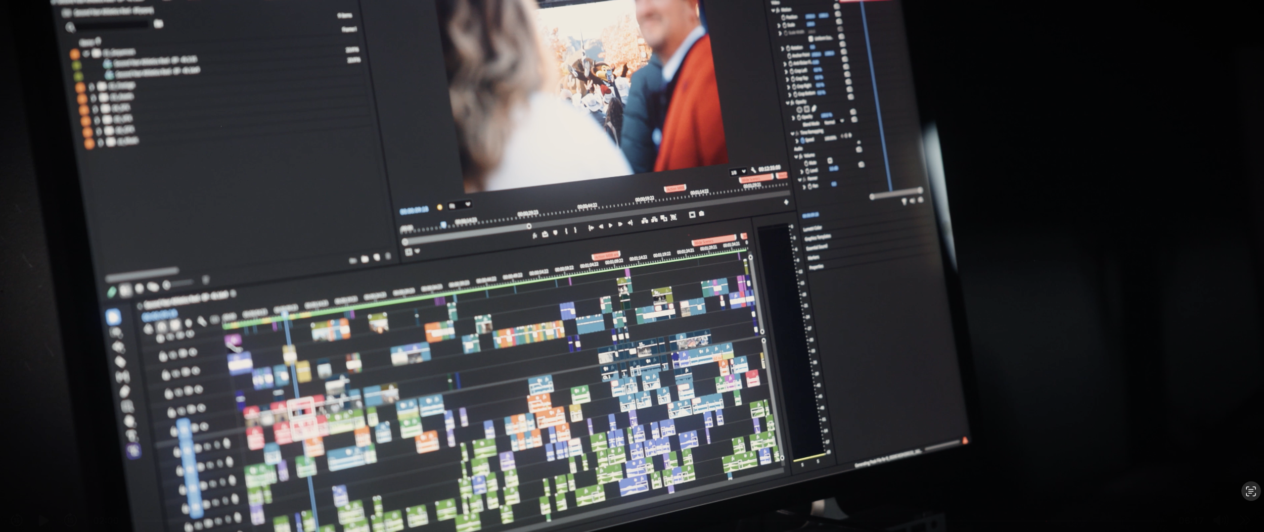 Computer screen showing a video editing software with a timeline of multiple colorful clips and a preview of a video of two people in conversation.