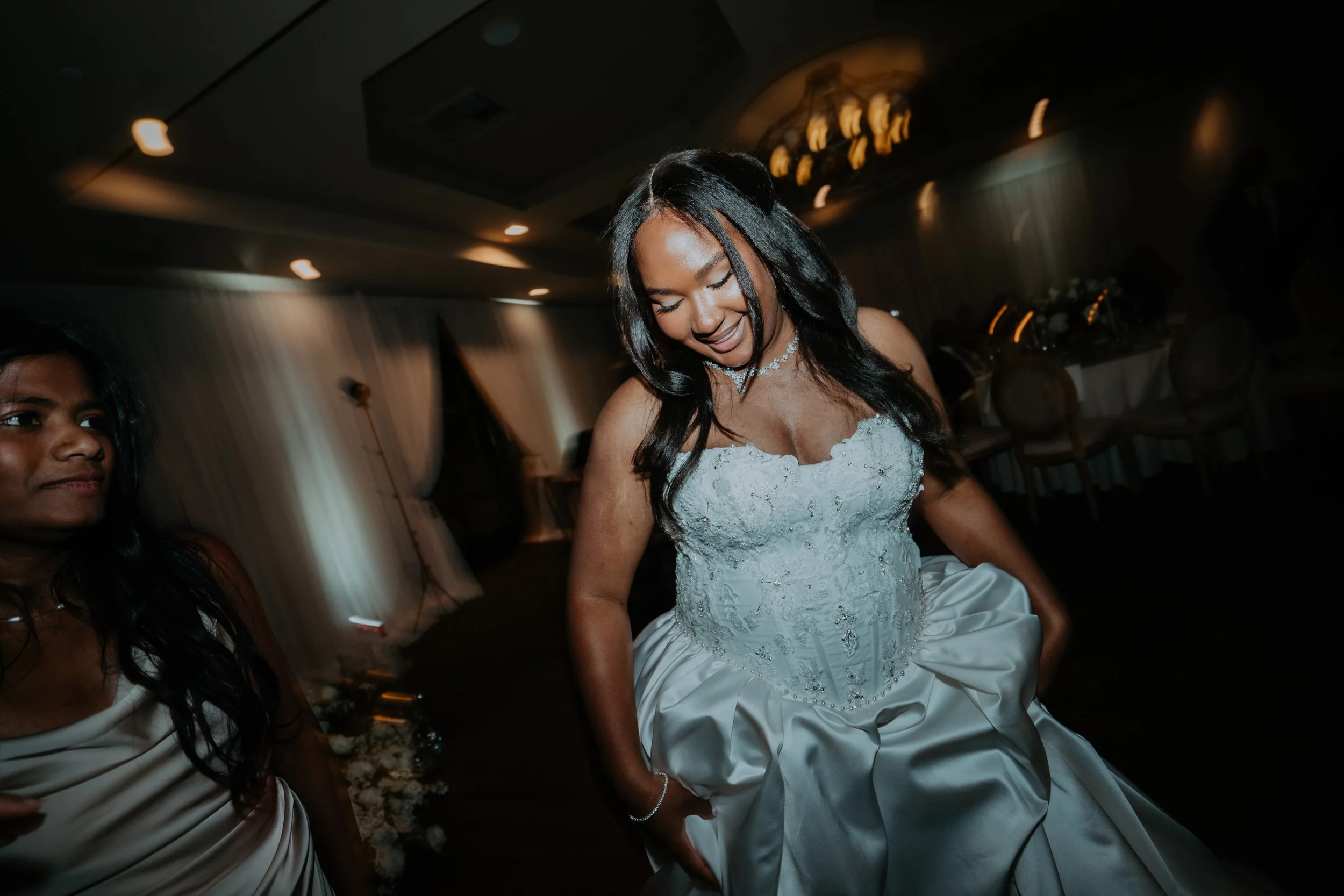 A woman in a white wedding dress dancing at a wedding reception.