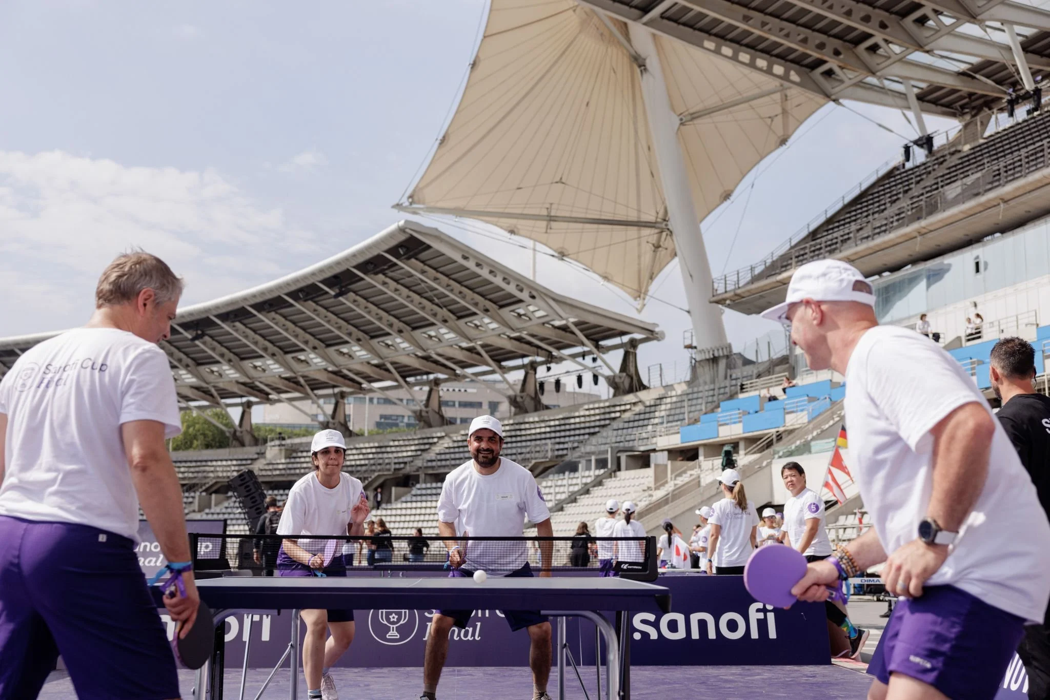 Four Sanofi employees compete in table tennis at the Sanofi Cup Final, wearing Sanofi-branded clothing