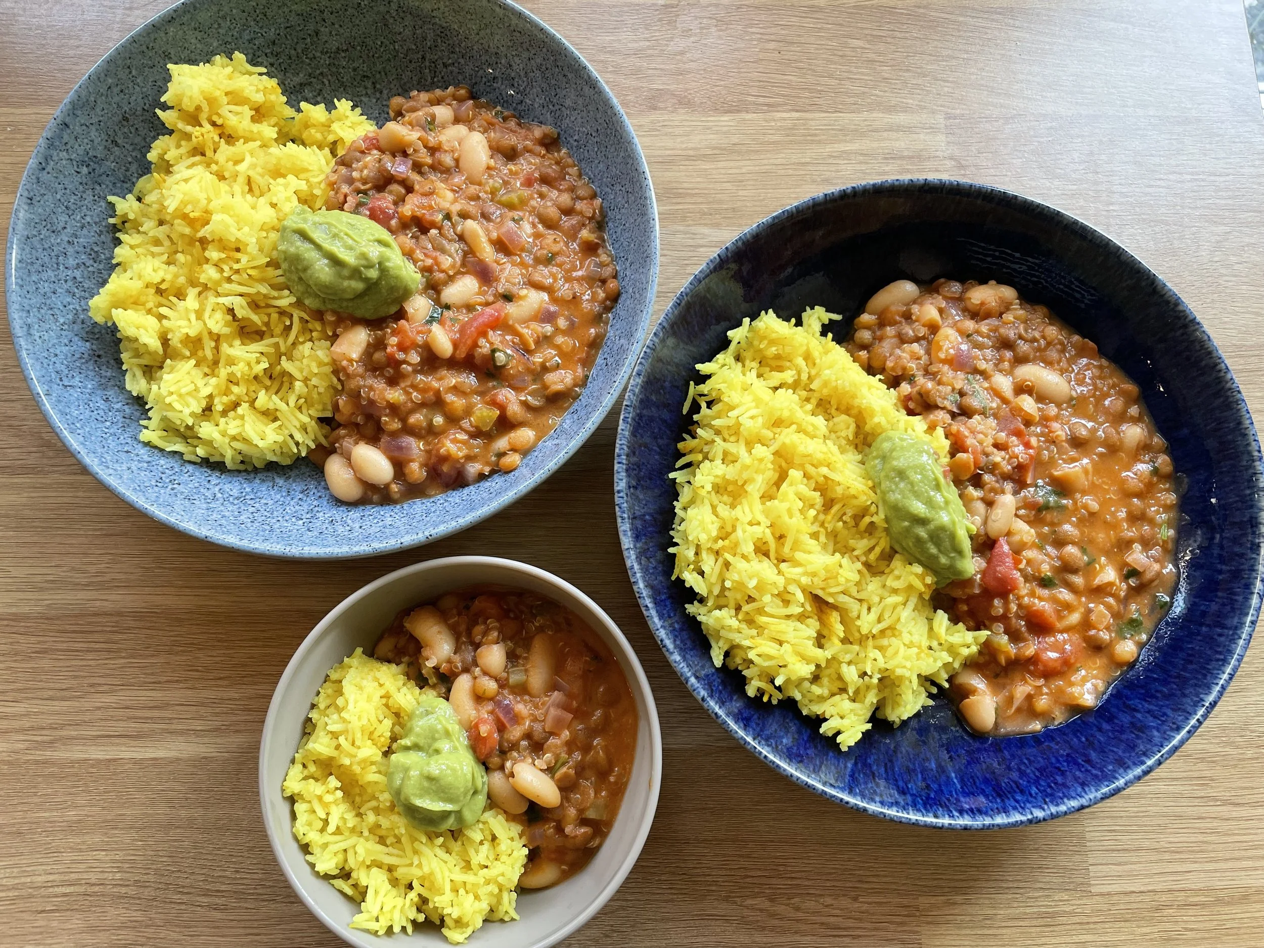 An image of two large bowls of chilli and rice, with one smaller bowl below
