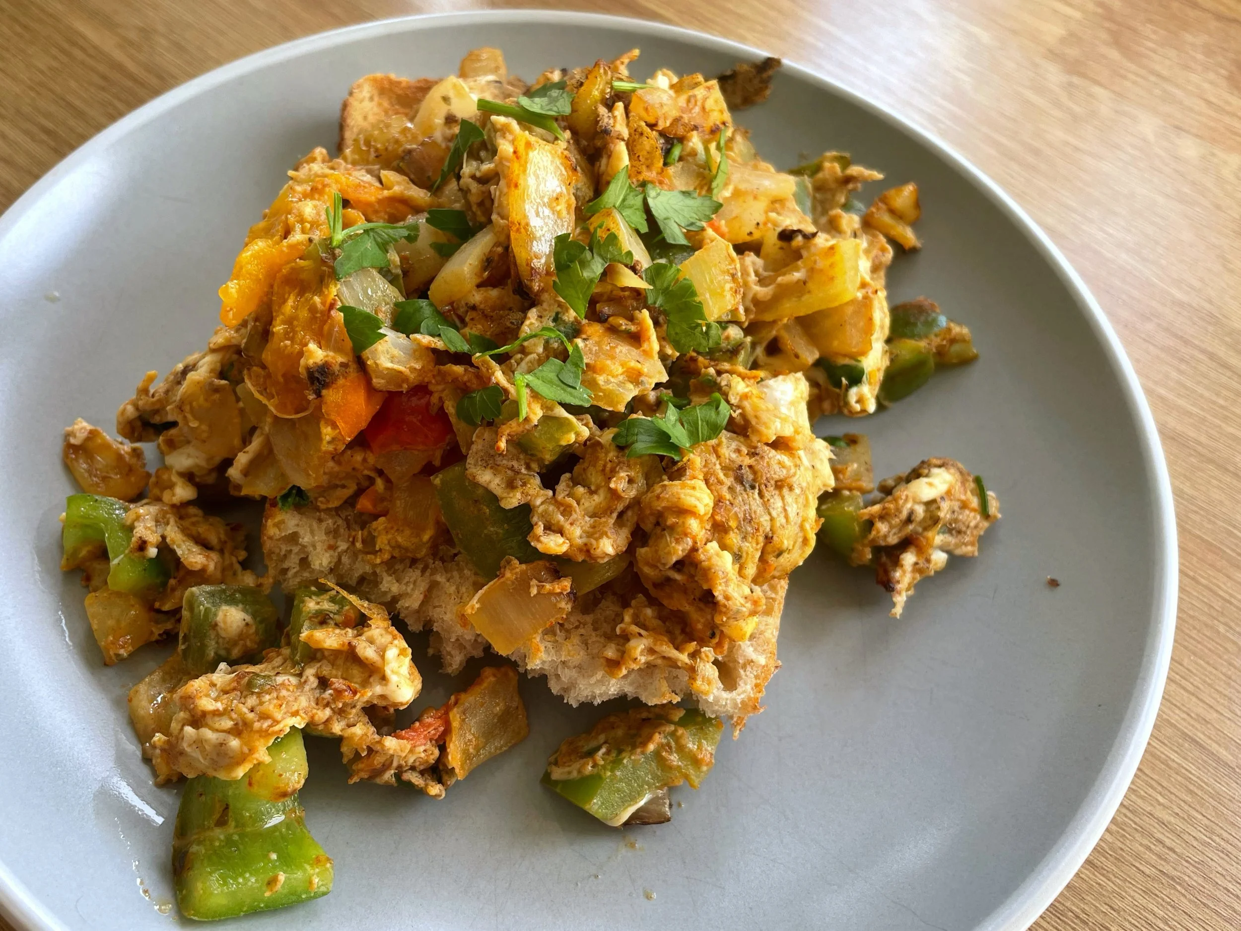 Image is of scrambled eggs with onion, pepper and tomatoes on a light blue plate