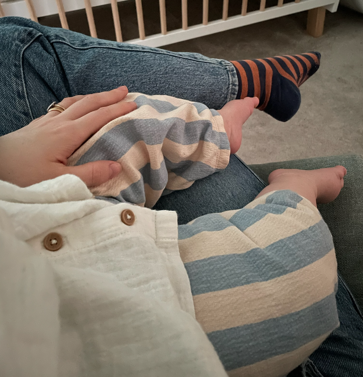 Image shows the legs and feet of a small child sitting on an adult's lap