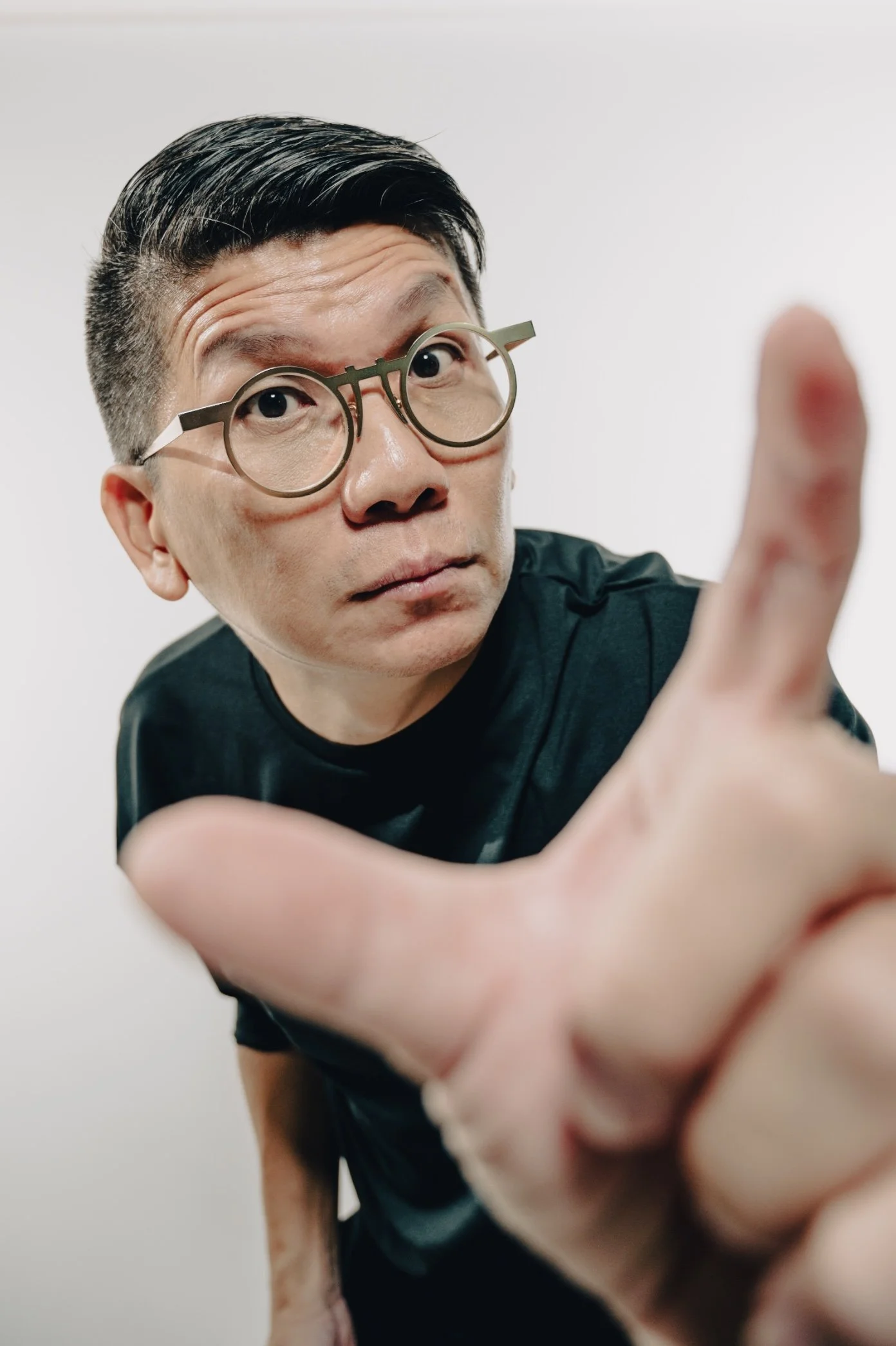 Man with glasses reaching towards the camera in a close-up shot