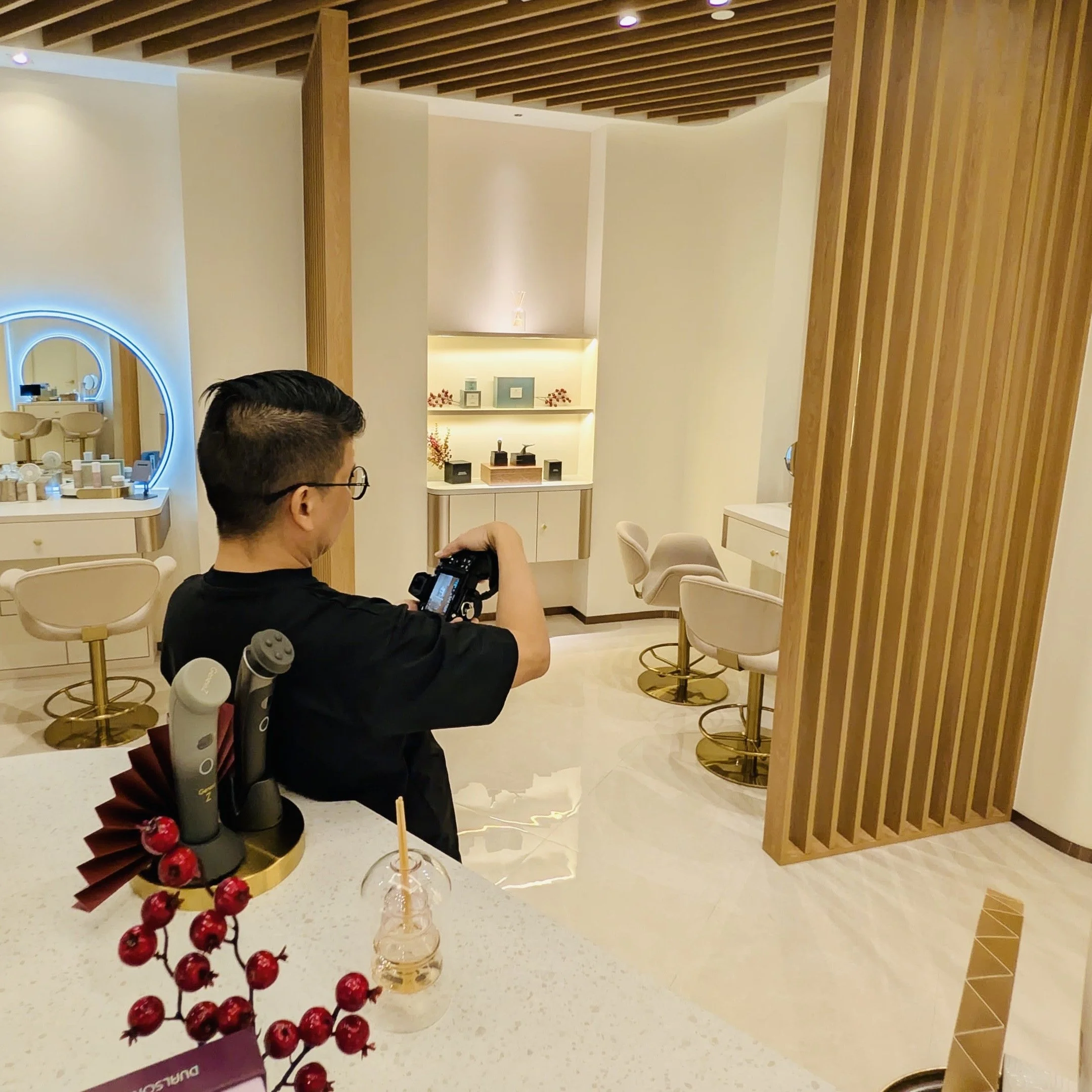 Person taking a photo inside a modern, well-lit beauty salon or spa with white and gold furnishings.
