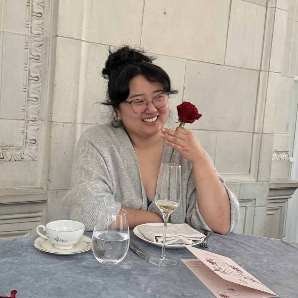 photo of Kyna smiling and holding a red rose