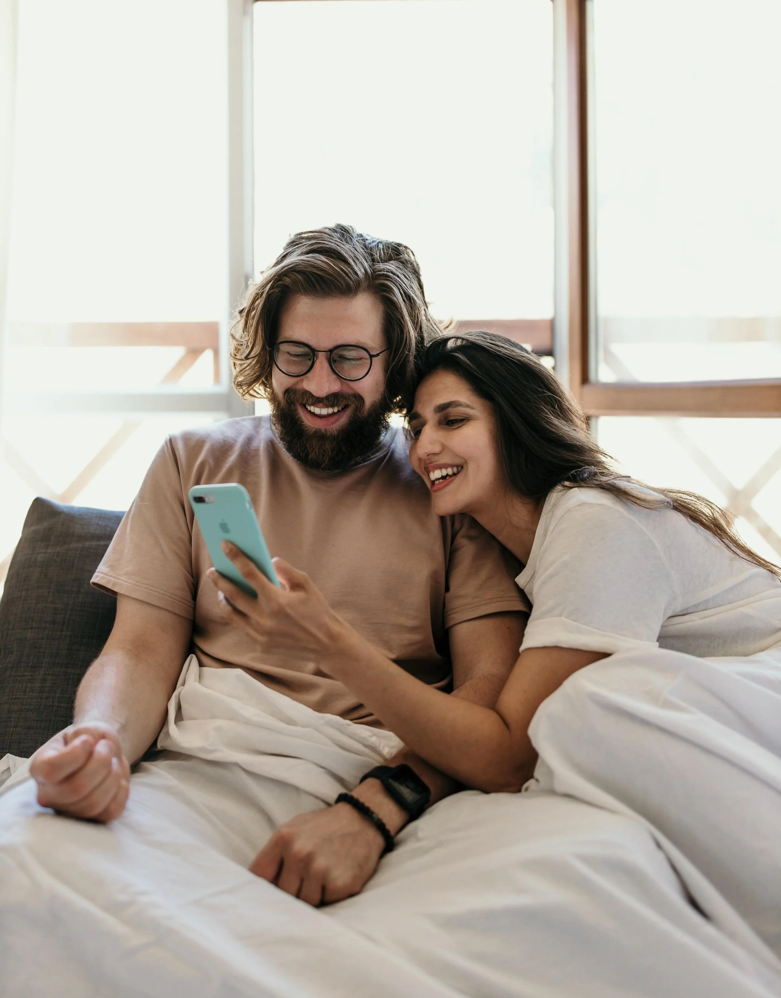 couple looking at social media together in bed and laughing