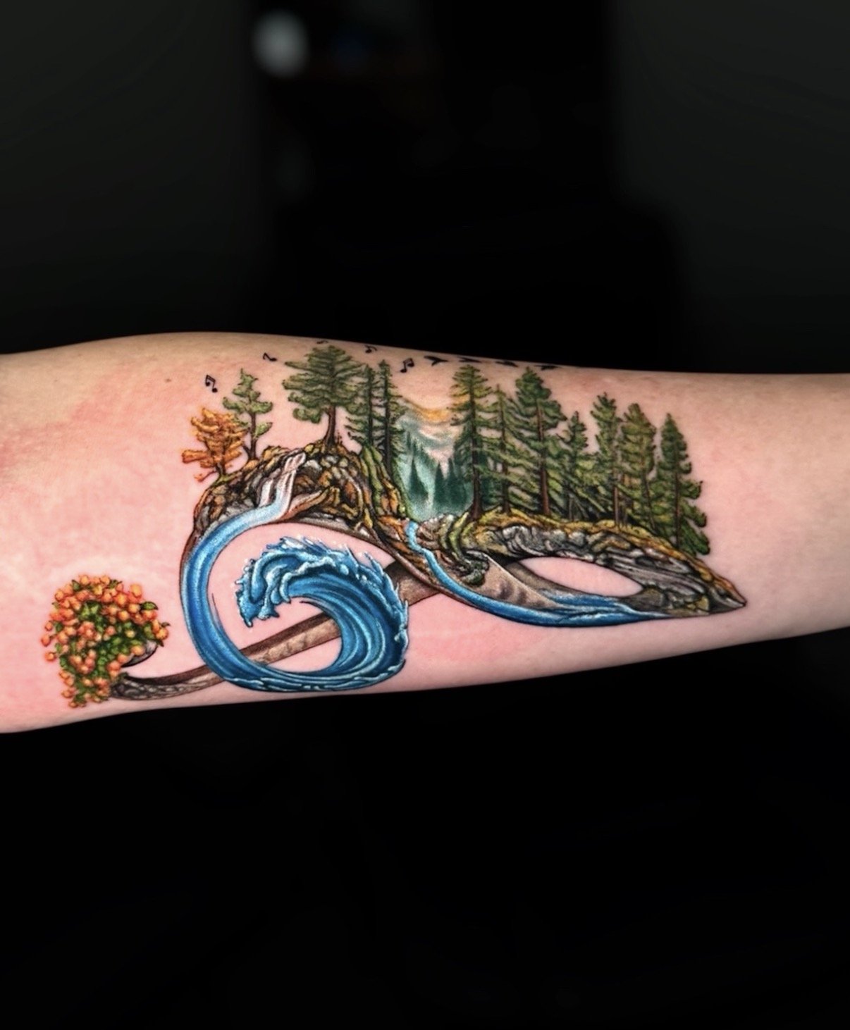 Colour nature tattoo combining a forest, waterfall, wave and flowers, by Chris Kennedy.