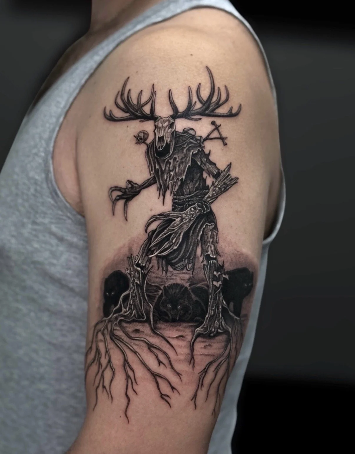 Black and grey antlered forest creature tattoo with trees, roots and woodland animals, by Chris Kennedy.