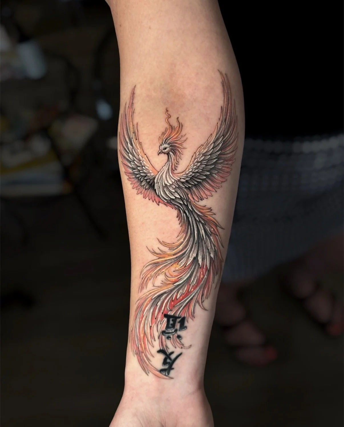 Black and grey phoenix tattoo with spread wings and red and orange feather accents, by Chris Kennedy.