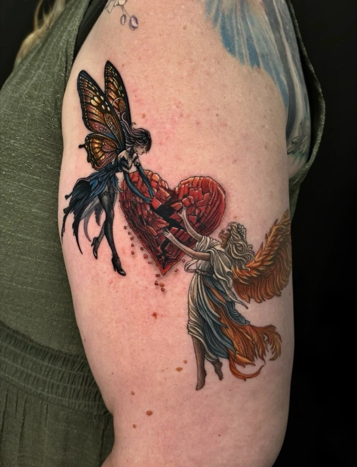 Colour tattoo of two winged figures beside a red heart, by Chris Kennedy.