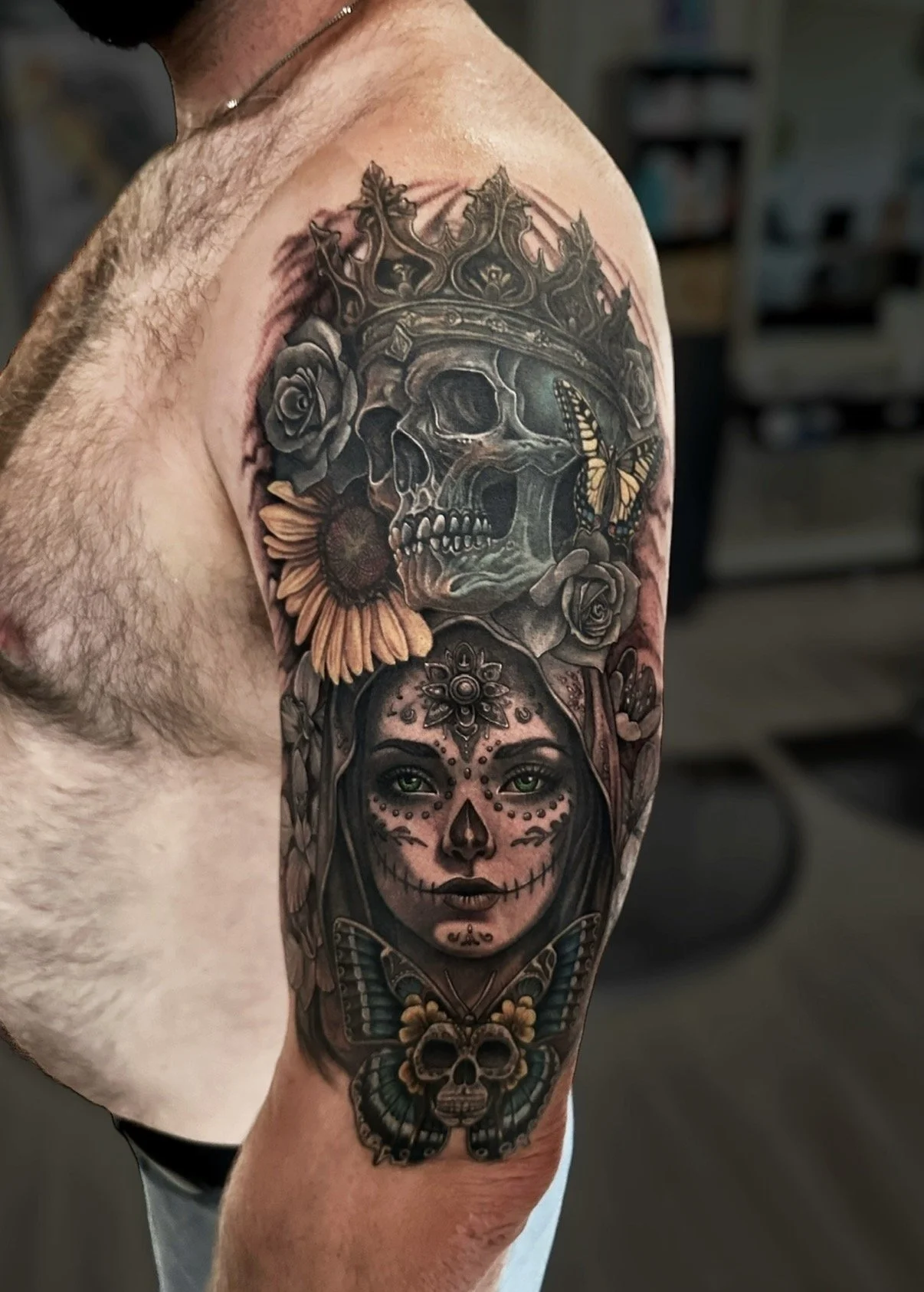 Colour and black and grey sleeve tattoo with a crowned skull, flowers, butterfly and Day of the Dead portrait, by Chris Kennedy.