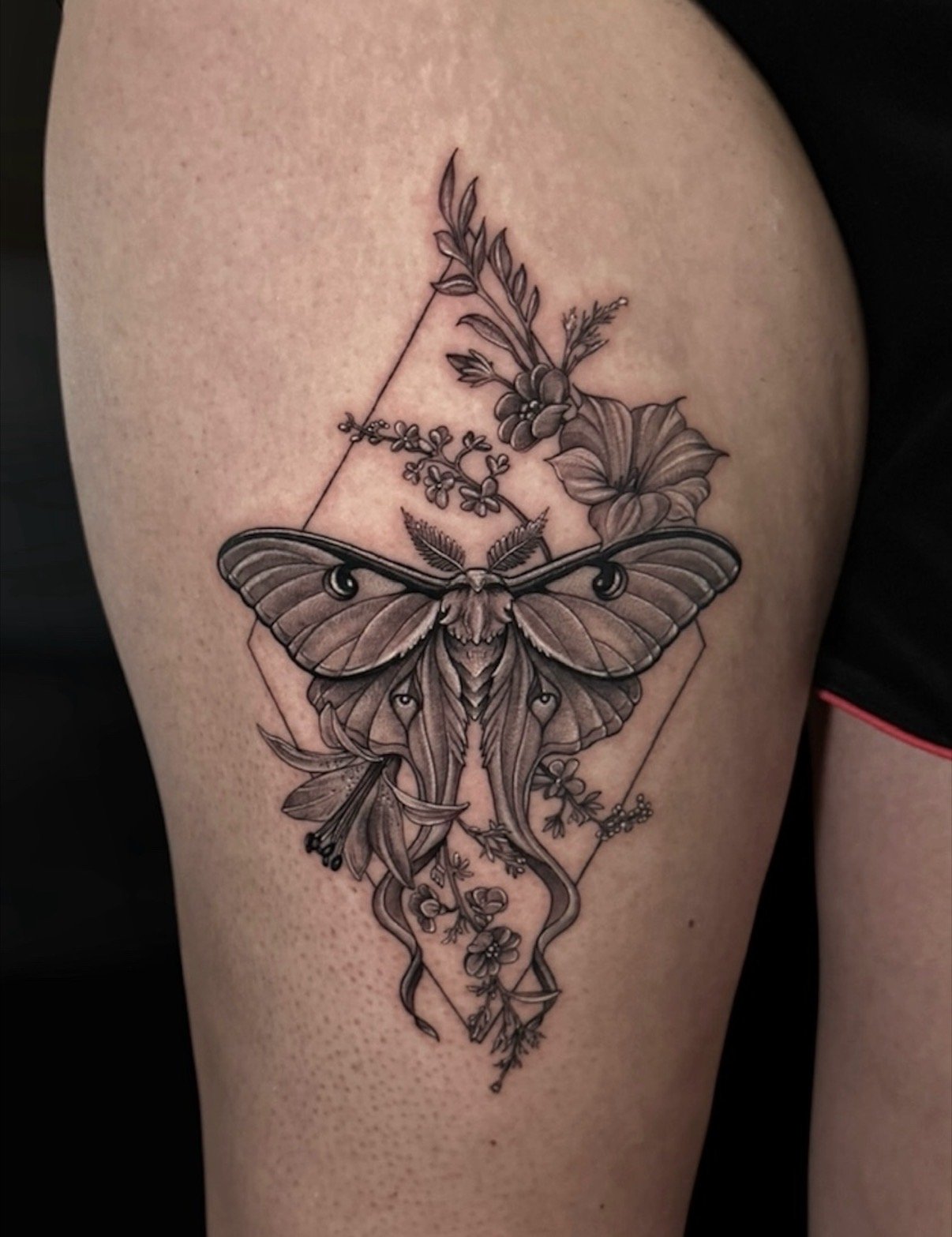 Black and grey luna moth tattoo framed by flowers and geometric lines, by Chris Kennedy.
