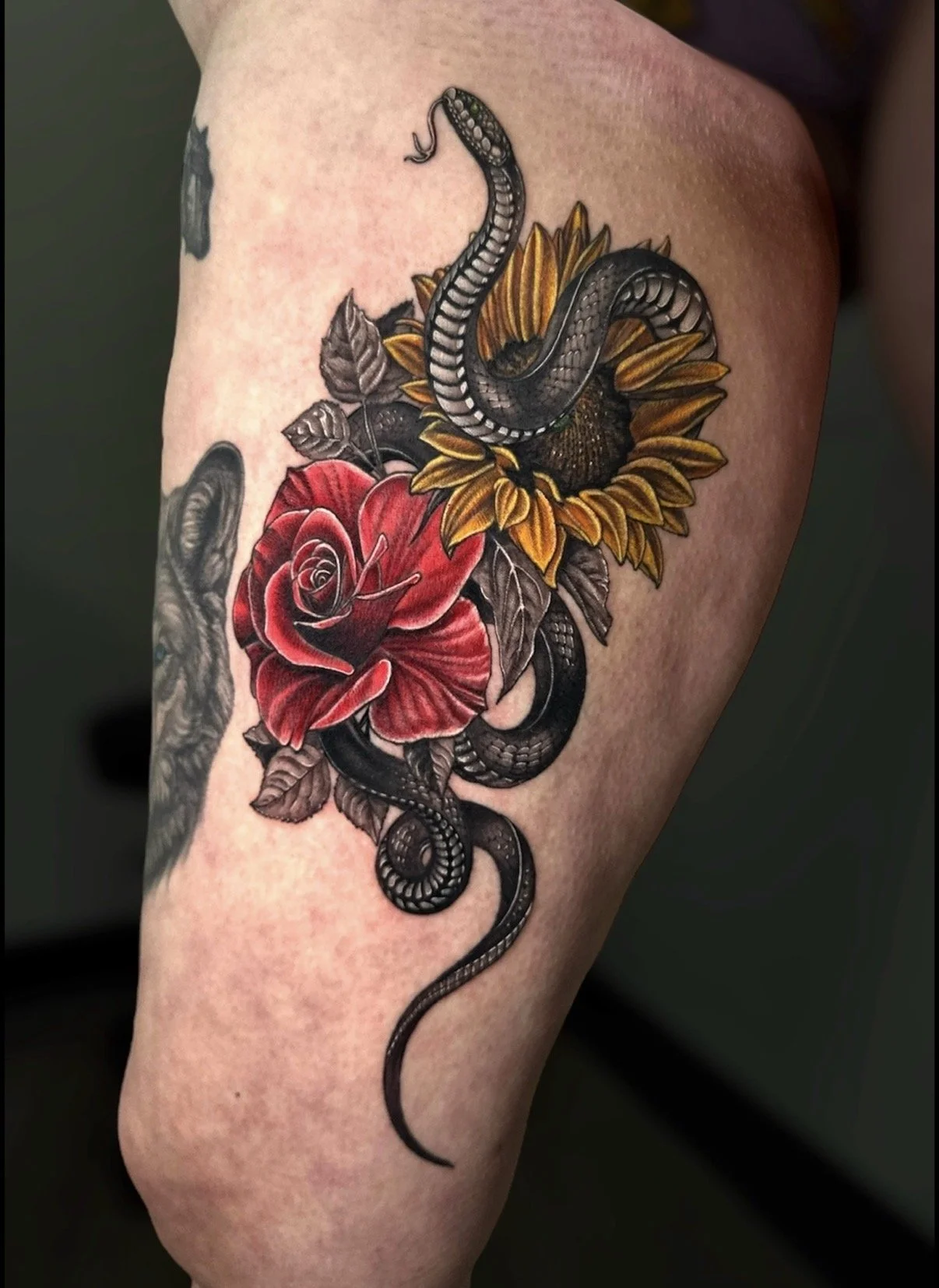 Snake tattoo winding around a red rose and yellow sunflower, by Chris Kennedy.