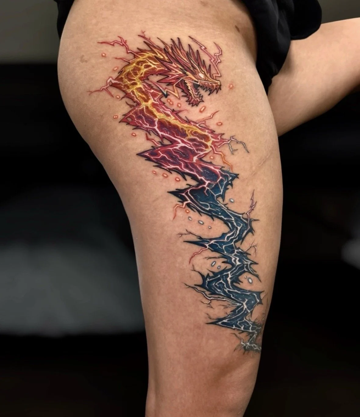 Colour lightning dragon tattoo fading from yellow and red to dark blue, by Chris Kennedy.