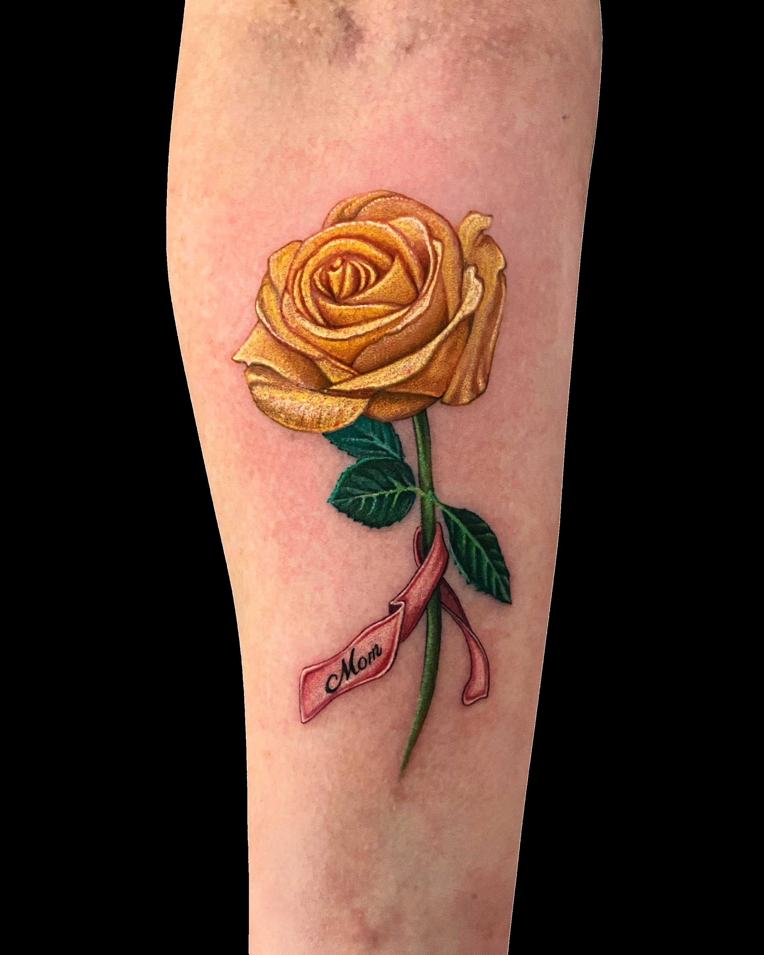Yellow rose tattoo with a green stem and leaves.