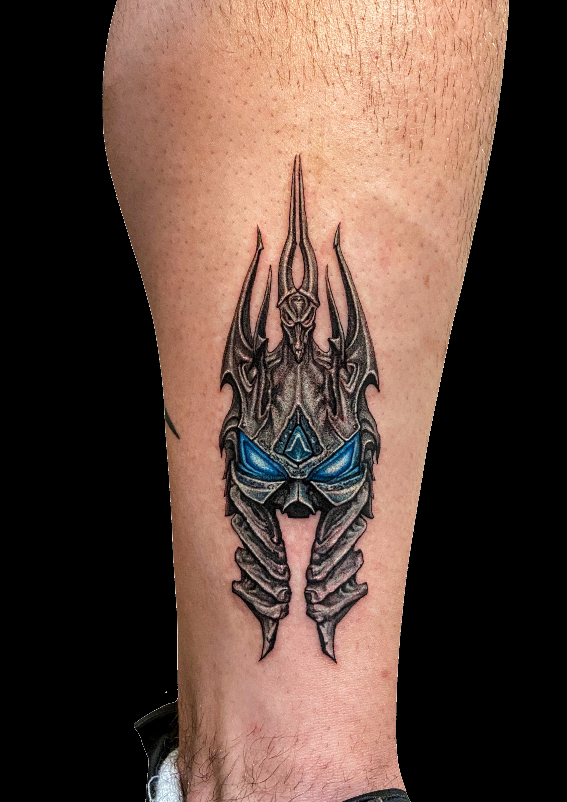 Dark spiked fantasy helmet tattoo with bright blue accents.