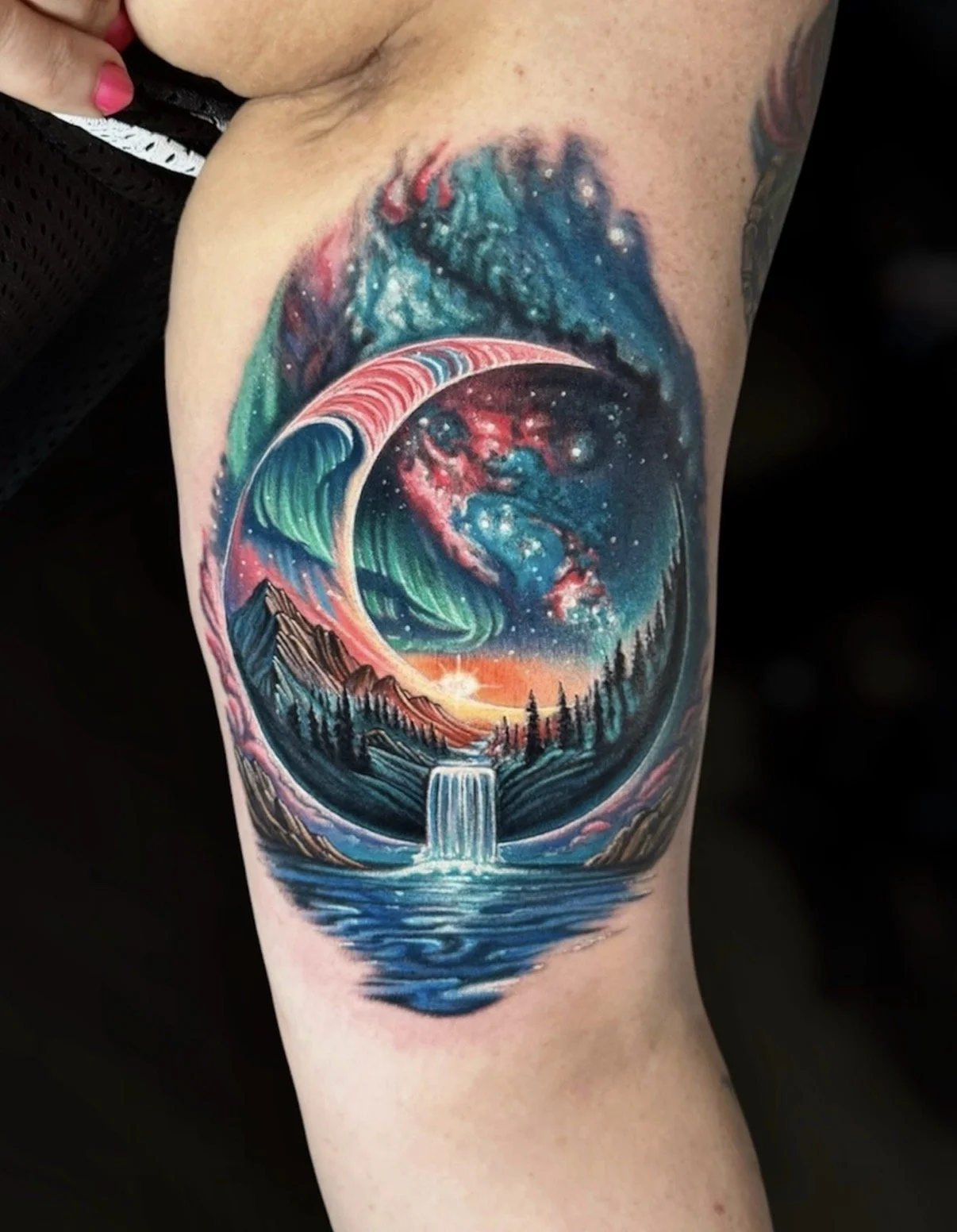 Colour crescent moon landscape tattoo with northern lights, mountains, forest and a waterfall, by Chris Kennedy.