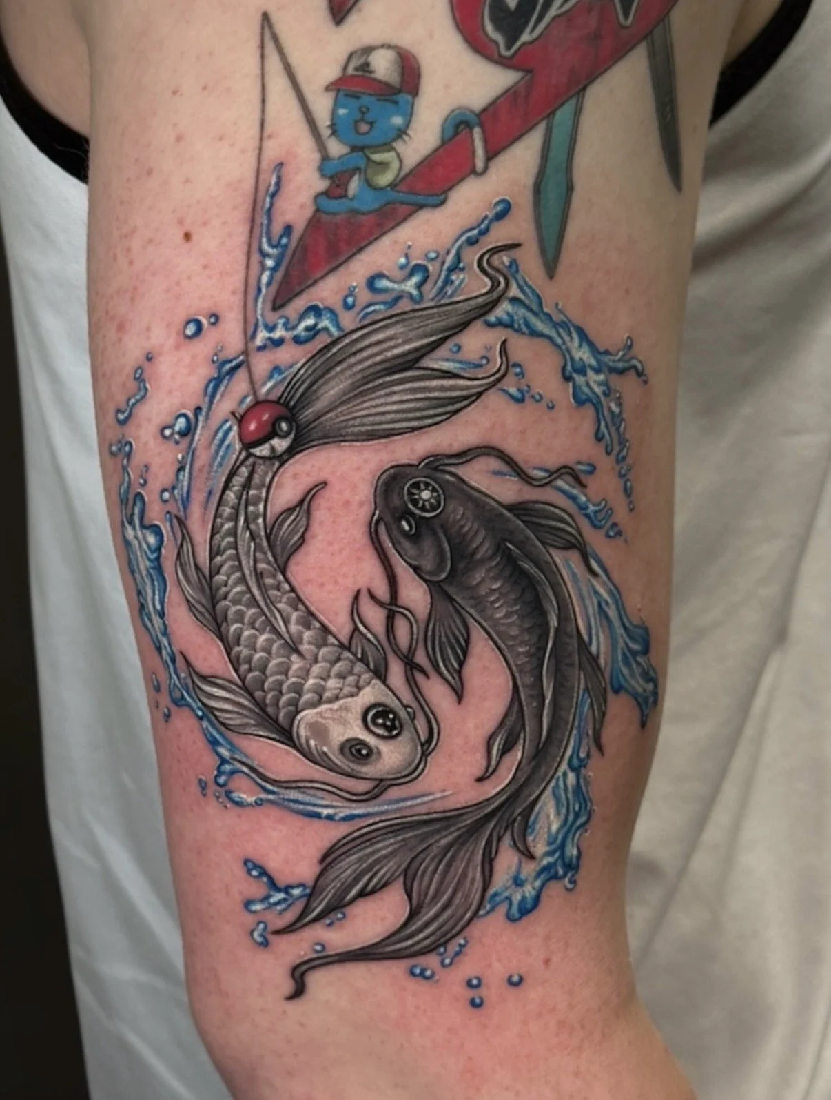 Black and grey koi fish tattoo with blue splashing water and a red Poké Ball, by Chris Kennedy.