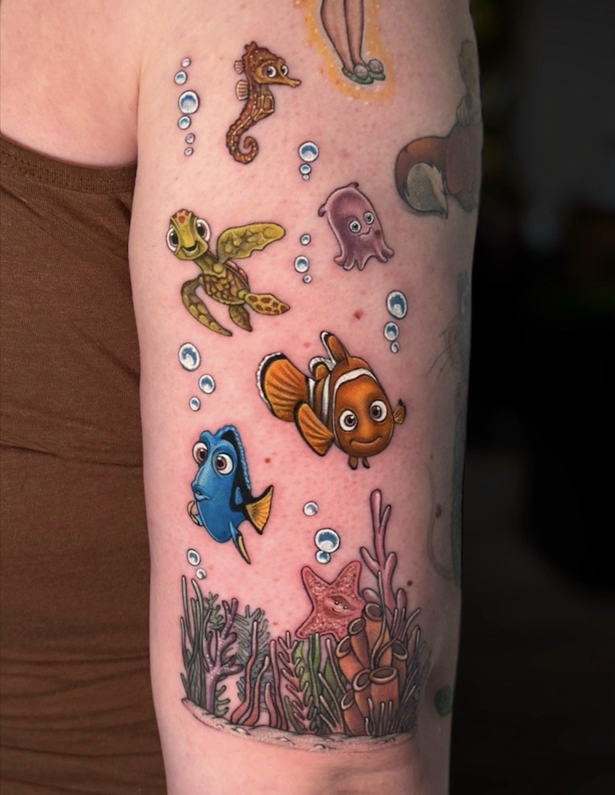 Colour Finding Nemo tattoo with Nemo, Dory, a sea turtle, seahorse, jellyfish and coral, by Chris Kennedy.