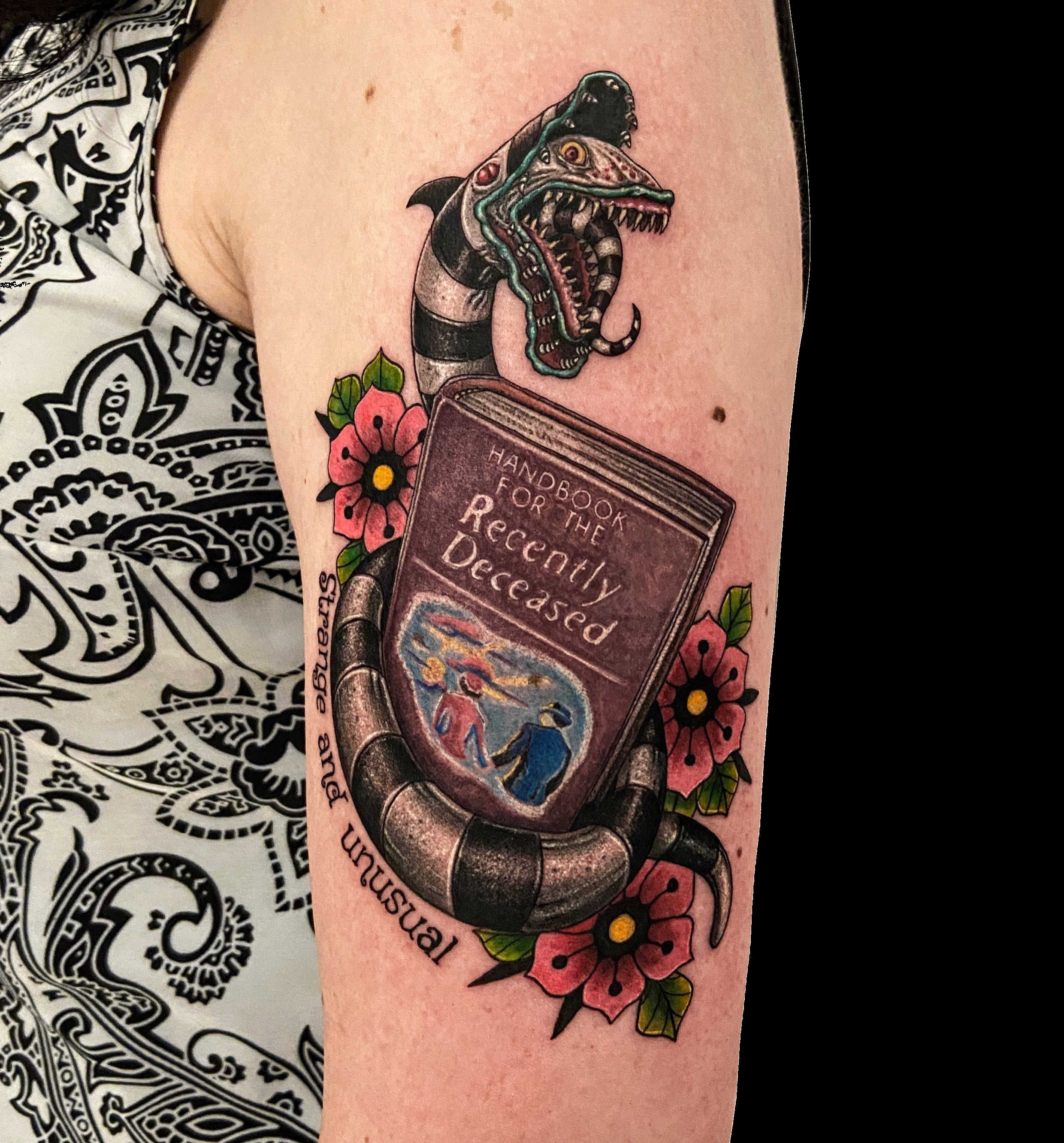 Book tattoo with a snake, hand and flowers.