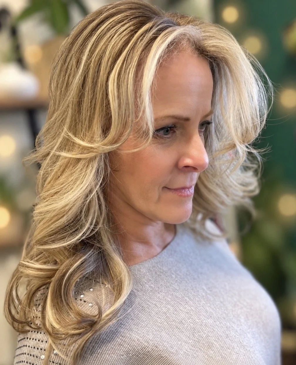 Long, layered blonde hair with soft highlights and dimensional gray blending at Zen Den Salon & Boutique in Encinitas, CA.