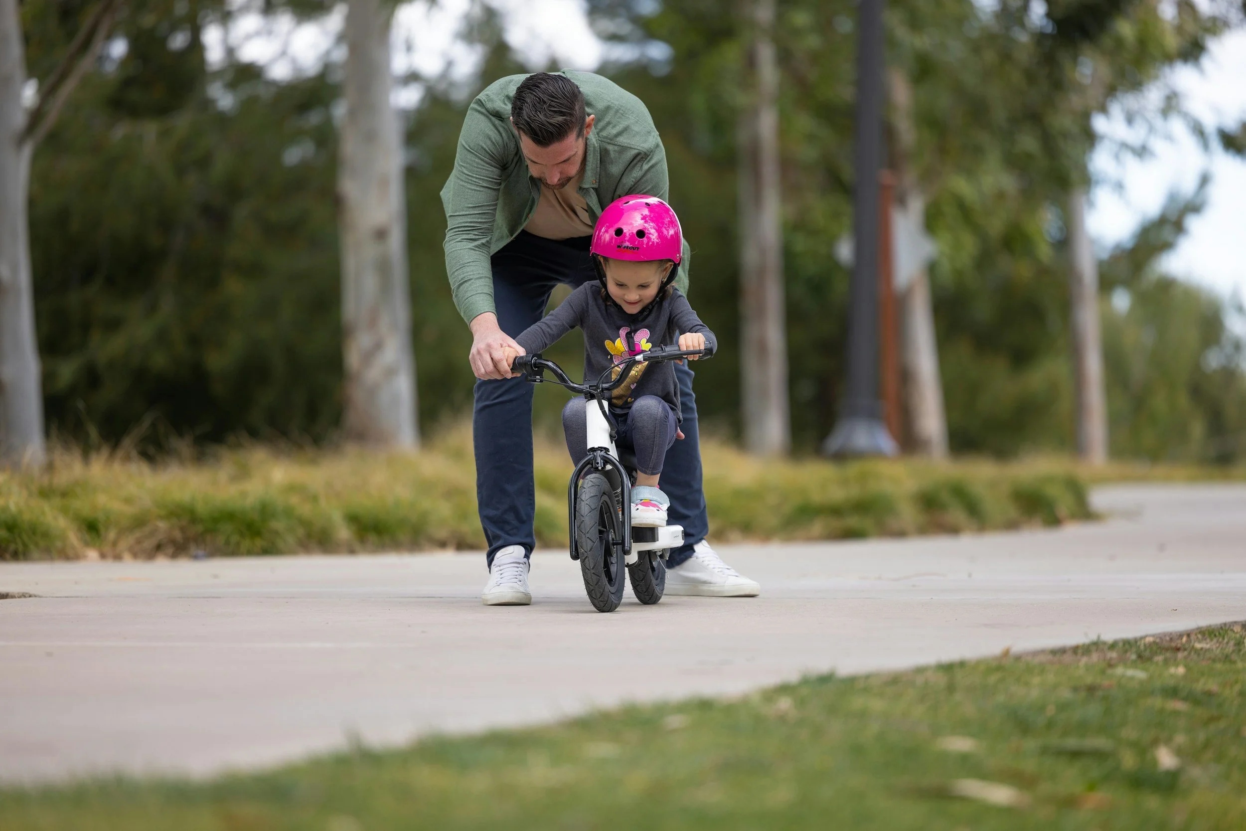A parent’s hand letting go of a child learning to ride a bike, symbolizing faith and trust.