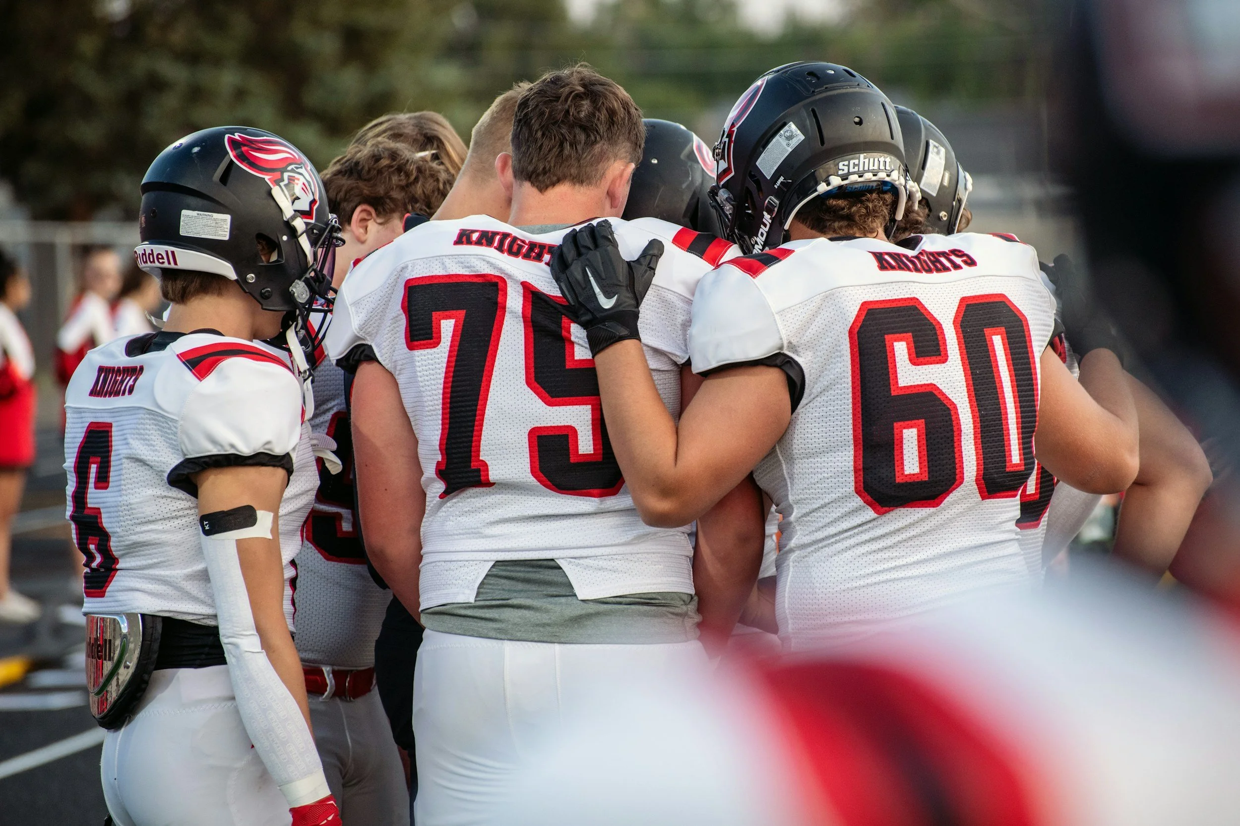 A football team standing shoulder to shoulder in a quiet huddle before the game begins