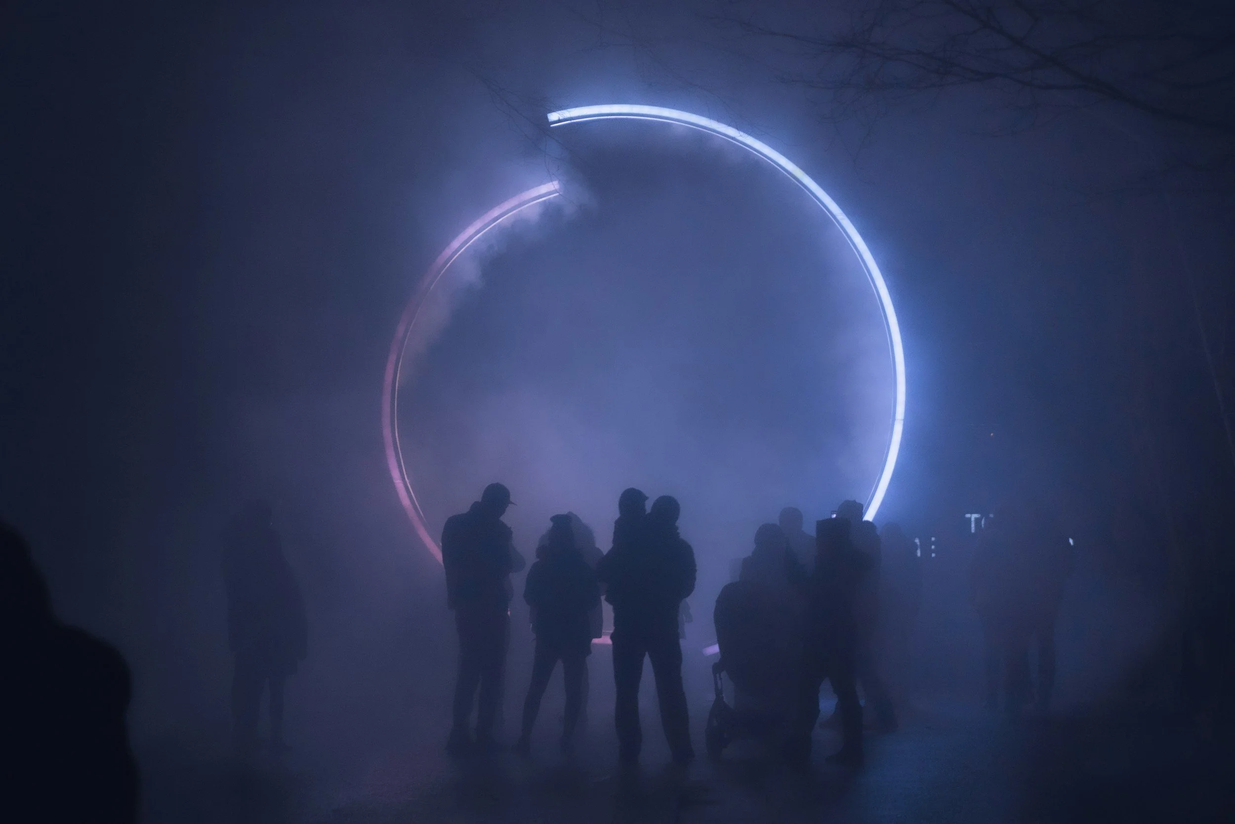 A small group standing close together in a circle under evening light
