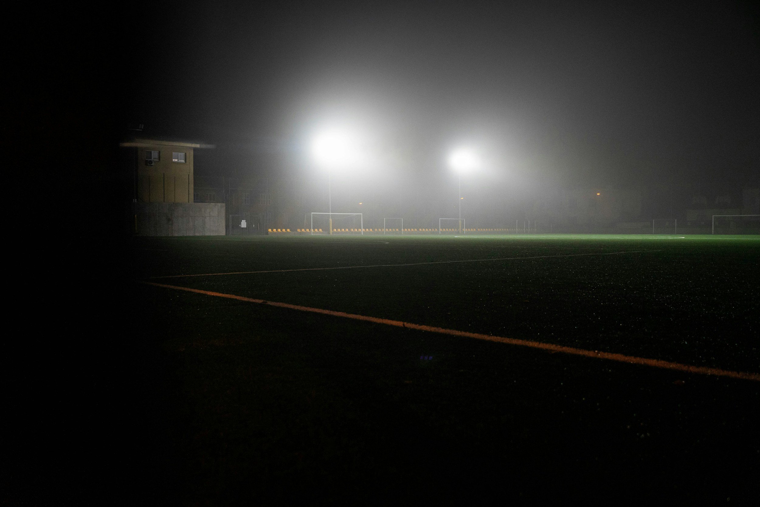 An empty football field lit at night, quiet and expectant