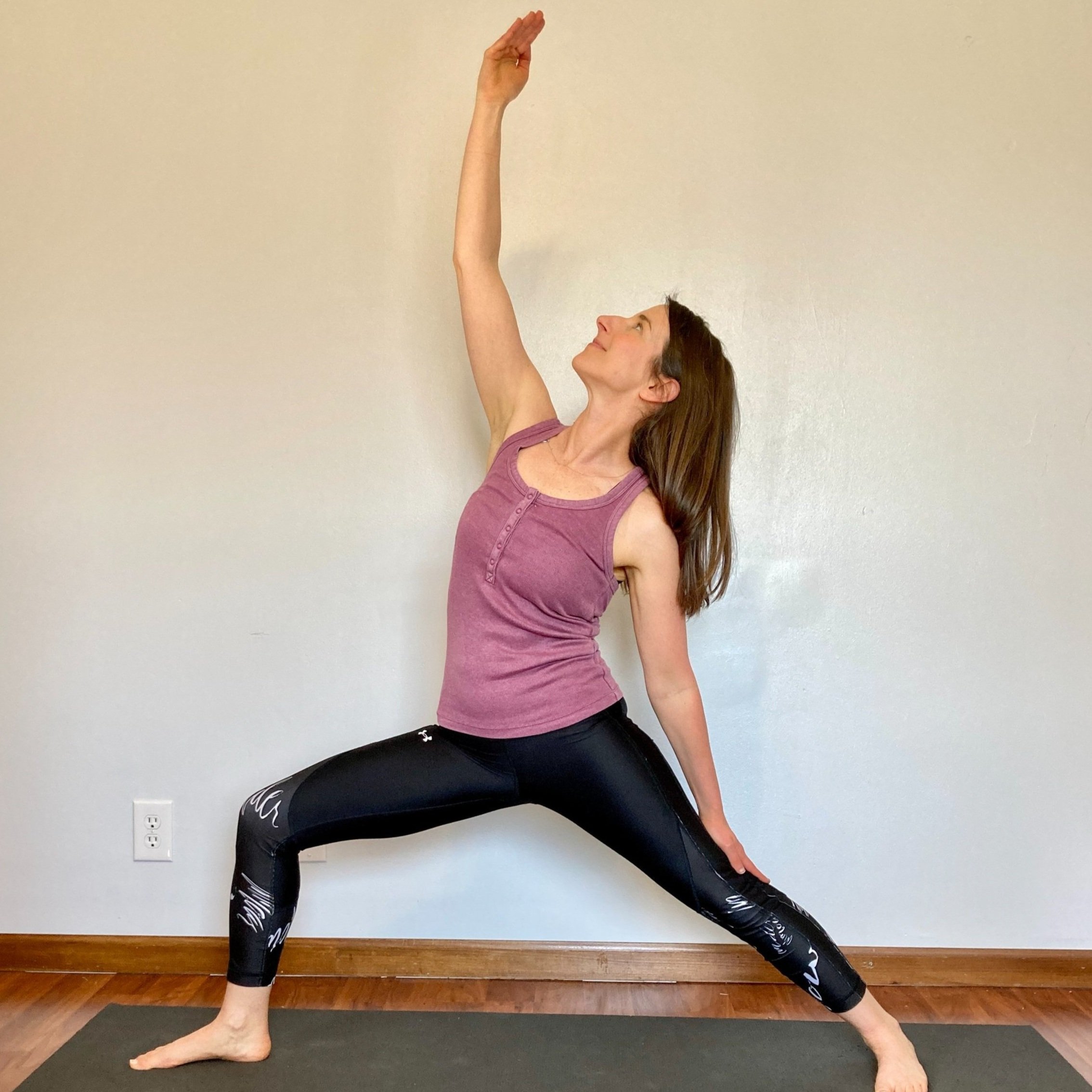 Woman practicing yoga in a lunge pose with one arm extended upward and the other hand on her thigh
