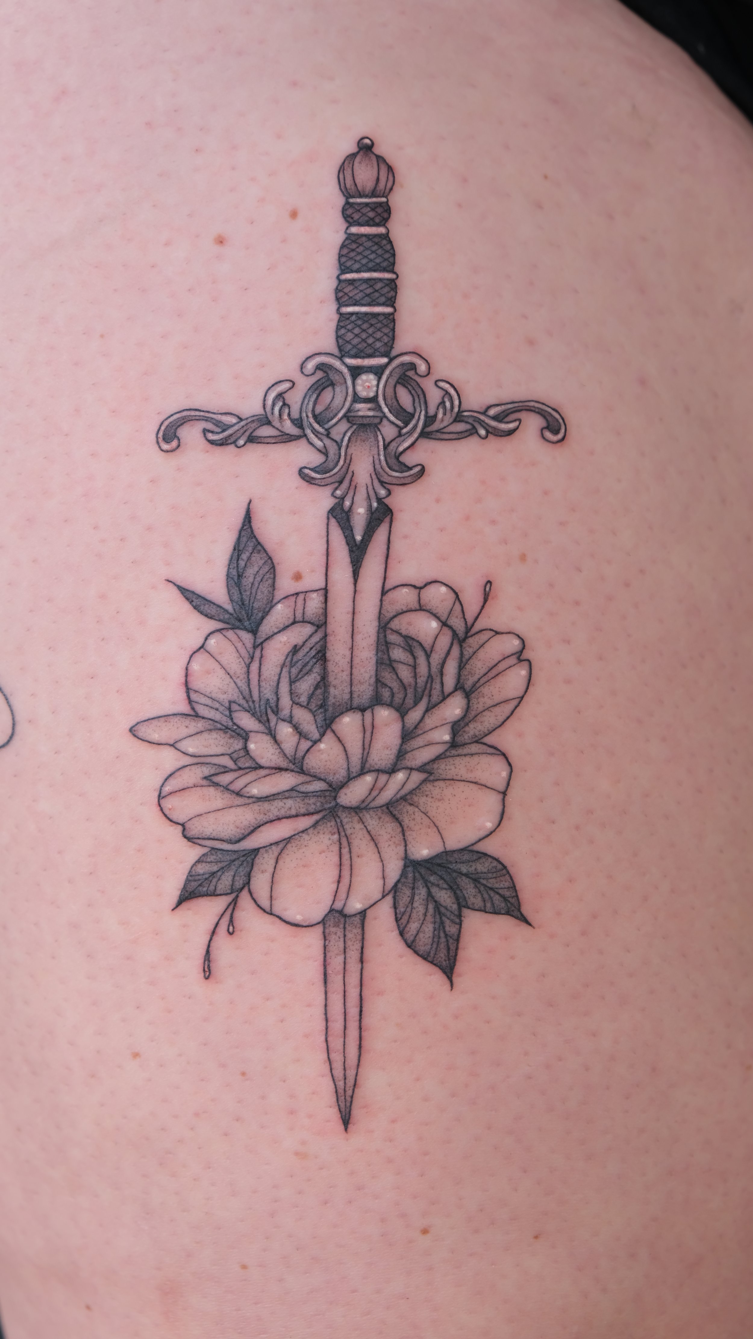 Tattoo of a sword piercing a flower with leaves.