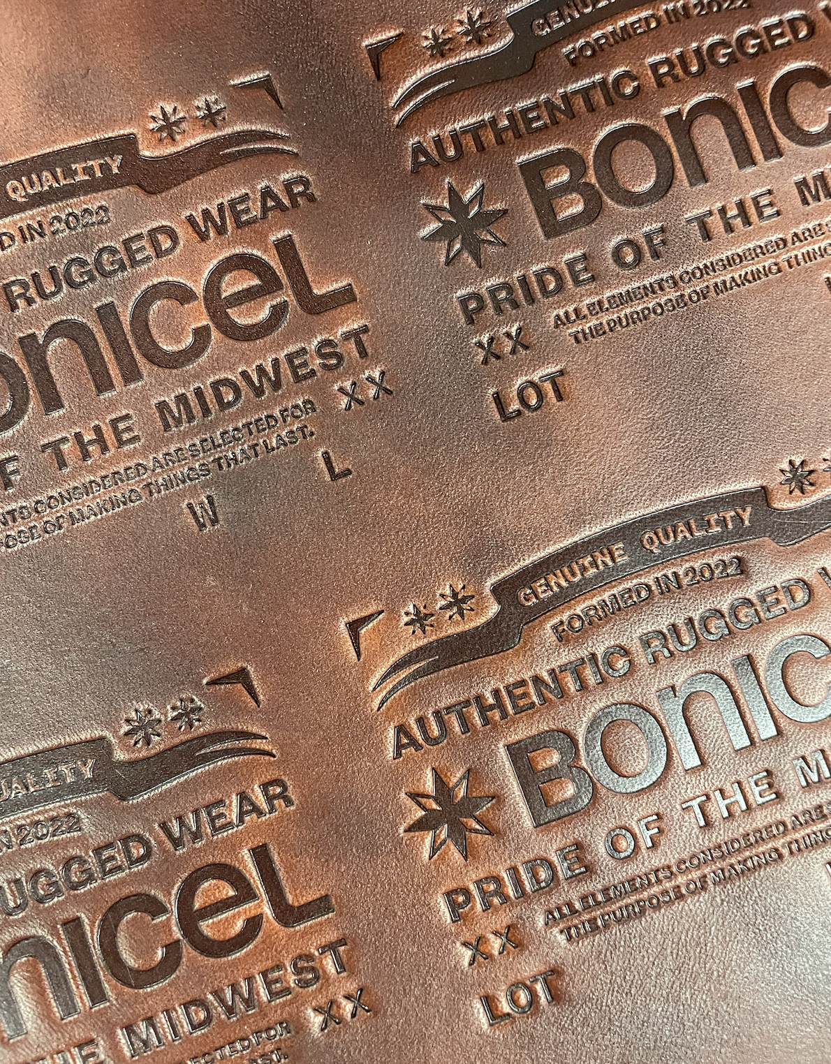 Close-up of embossed copper metal with engraved text and decorative elements about genuine rugged wear and pride of the Midwest and the Mountain regions, including lot and size information.