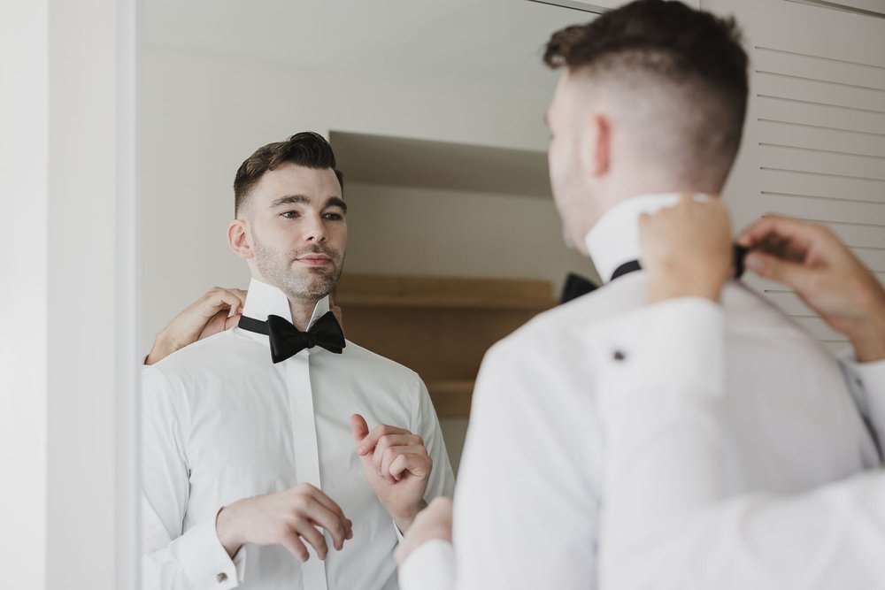 Two grooms getting ready together on wedding morning