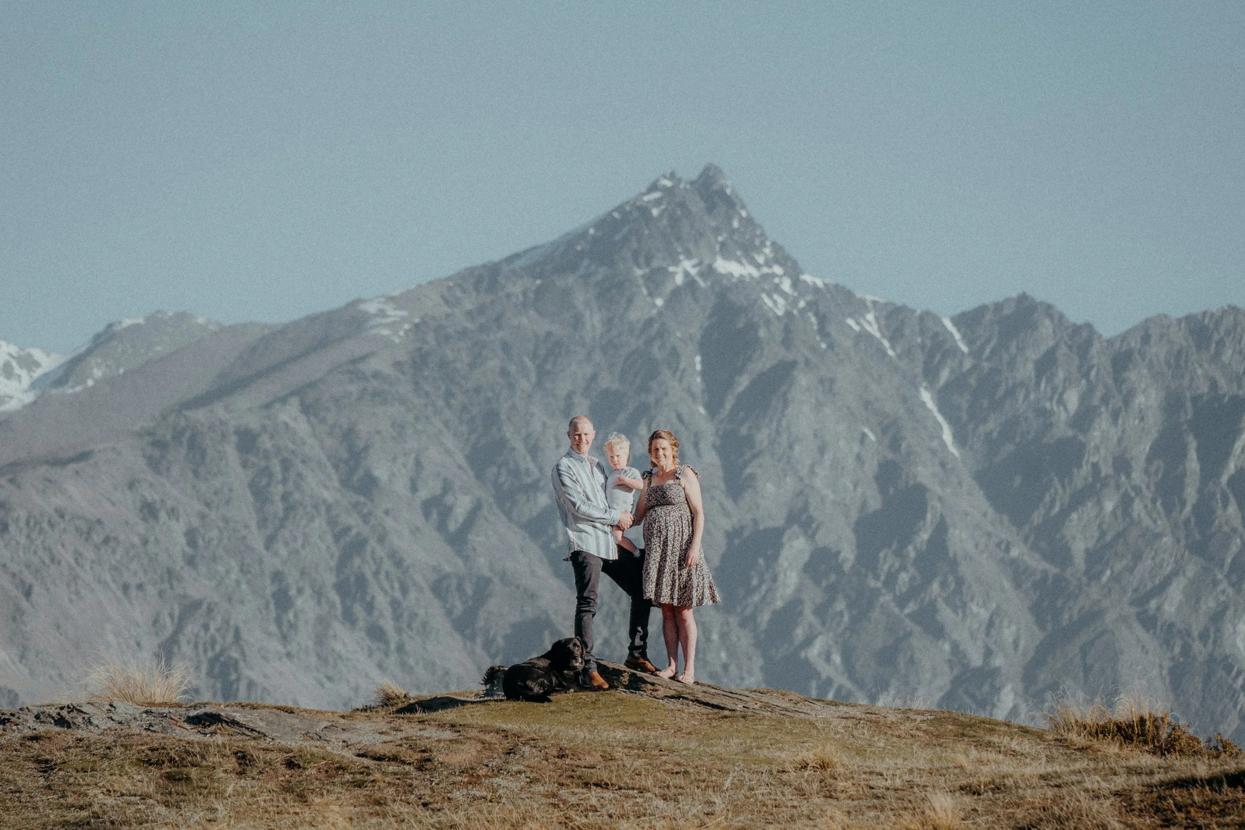 Wide angle shot of family posing in front of snow capped ben lomond range