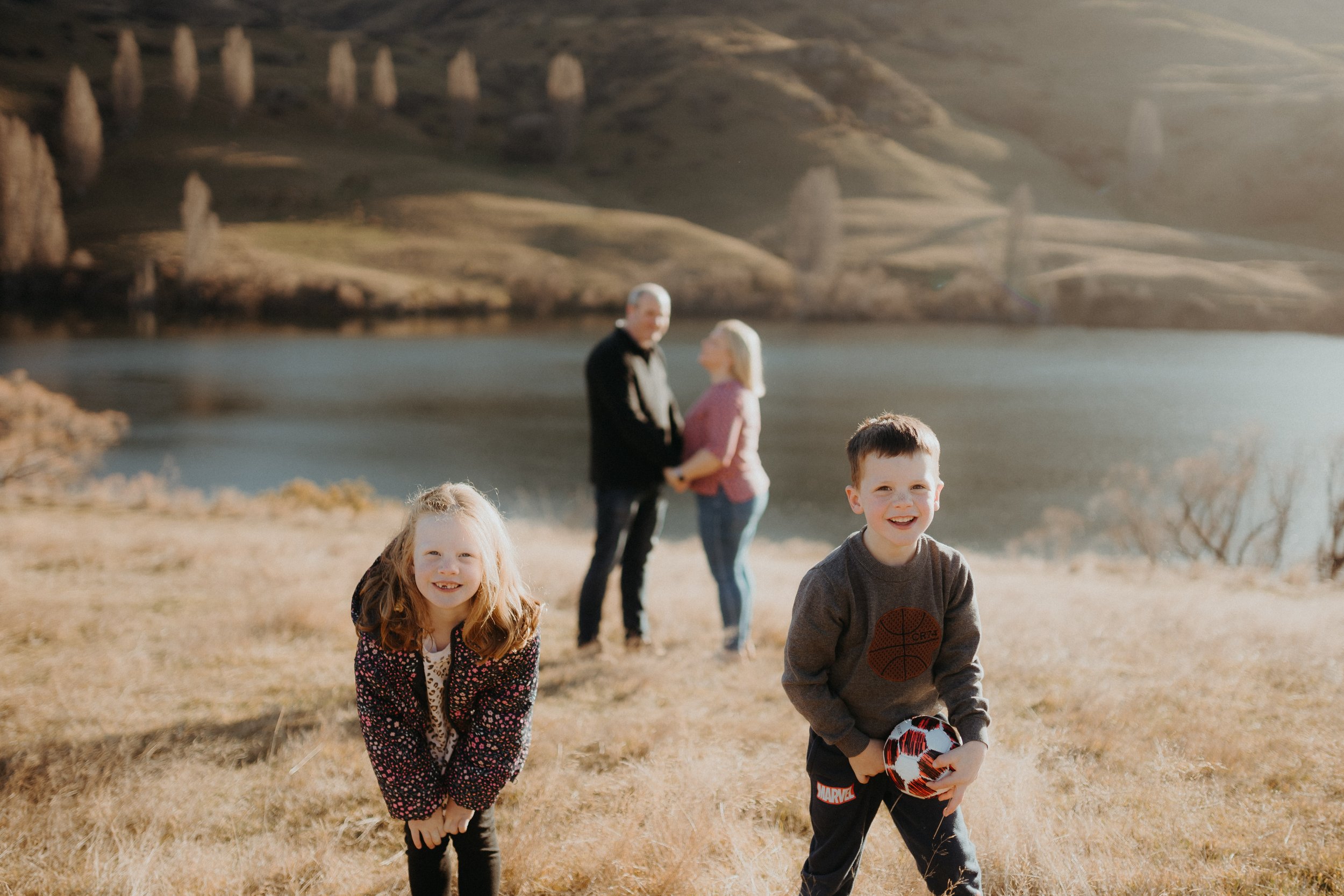 Siblings laughing while Mum and Dad kiss in background