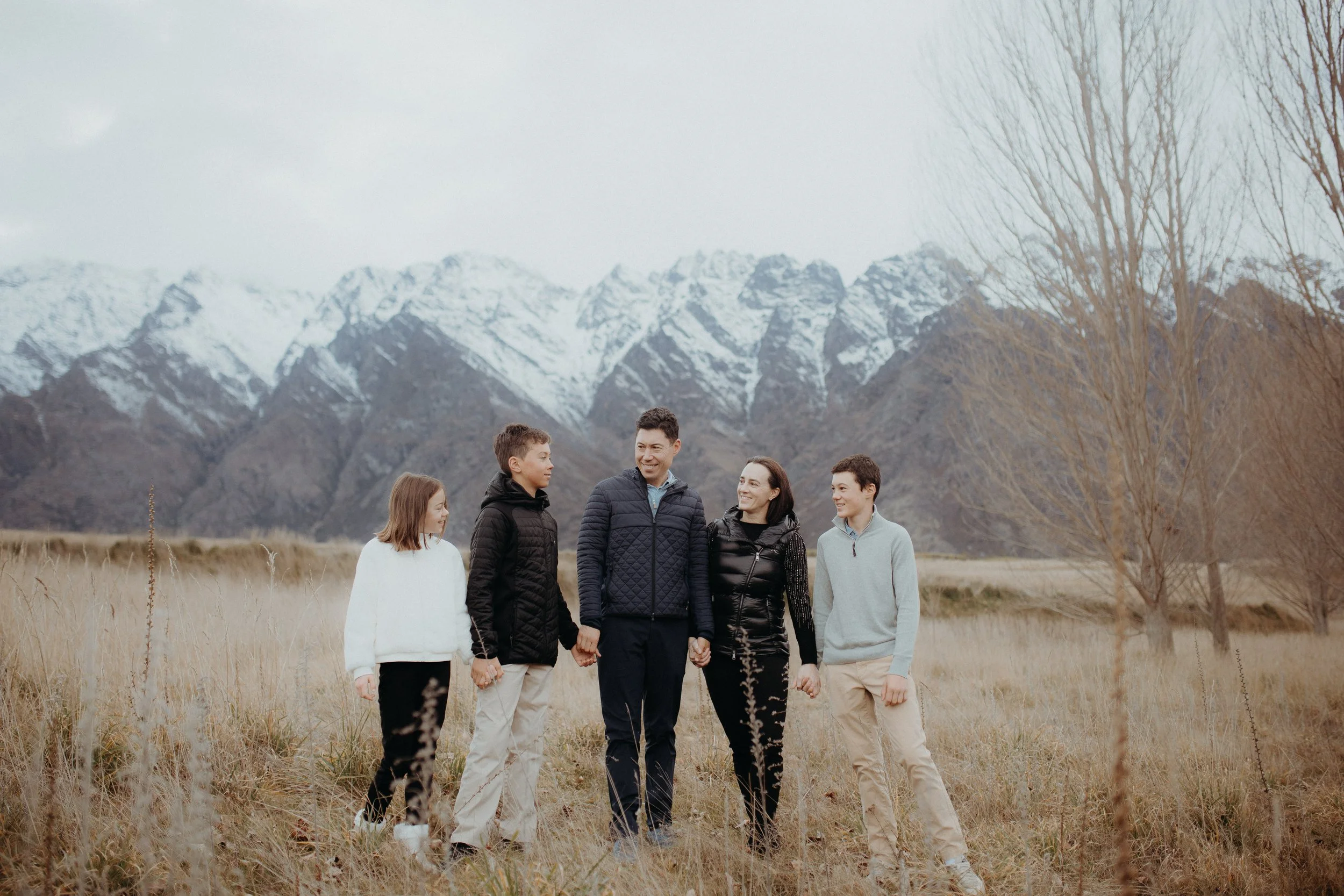 Family of 5 posing in front of snow filled remarkable mountains