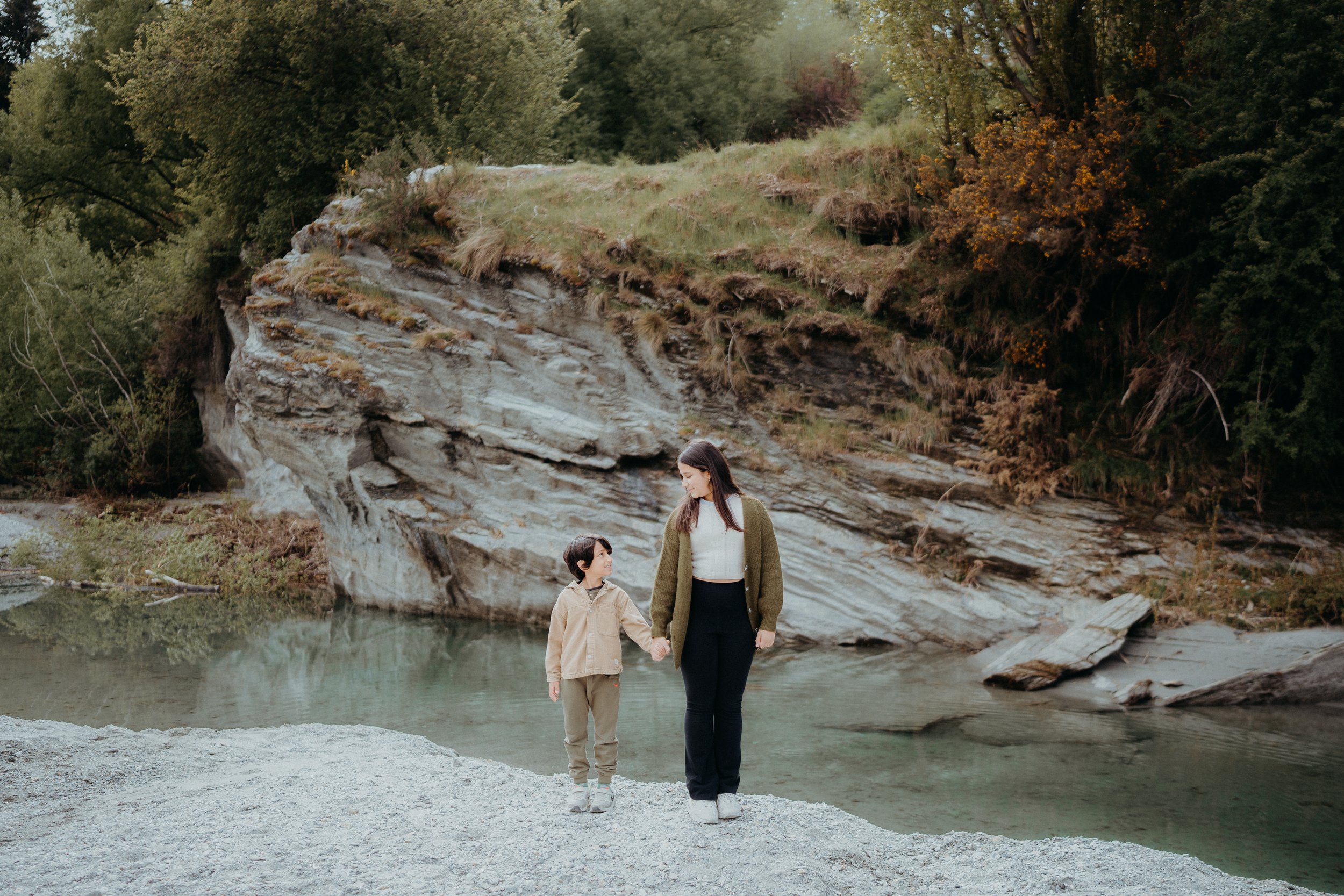 Mother and son standing side by side, holding hands.