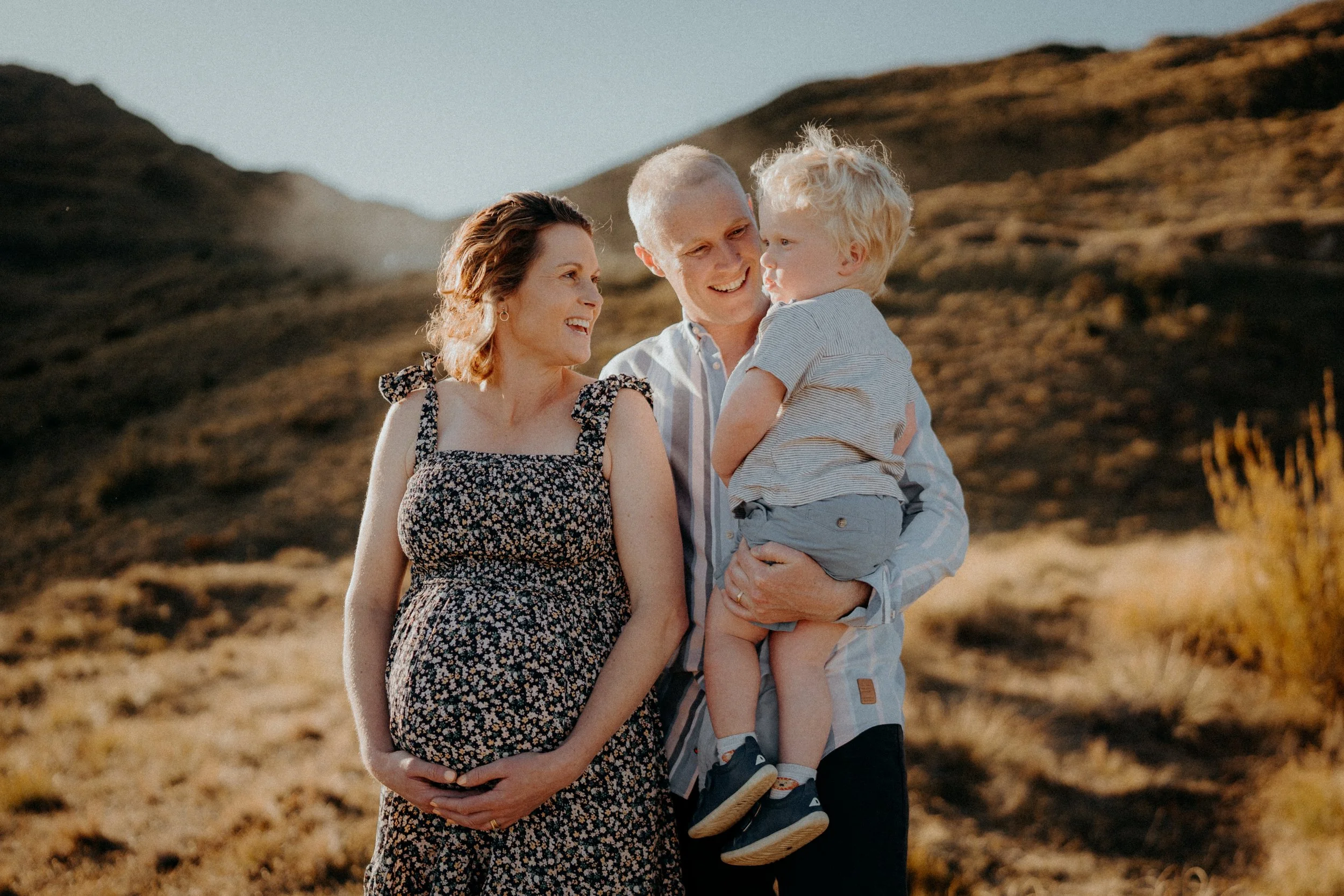 Pregnant mother and father smiling at their son