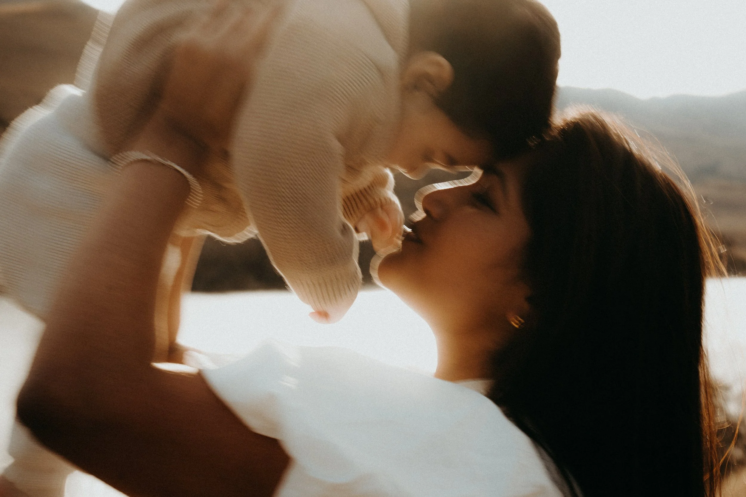 Close up golden hour shot of mother holding baby to forehead