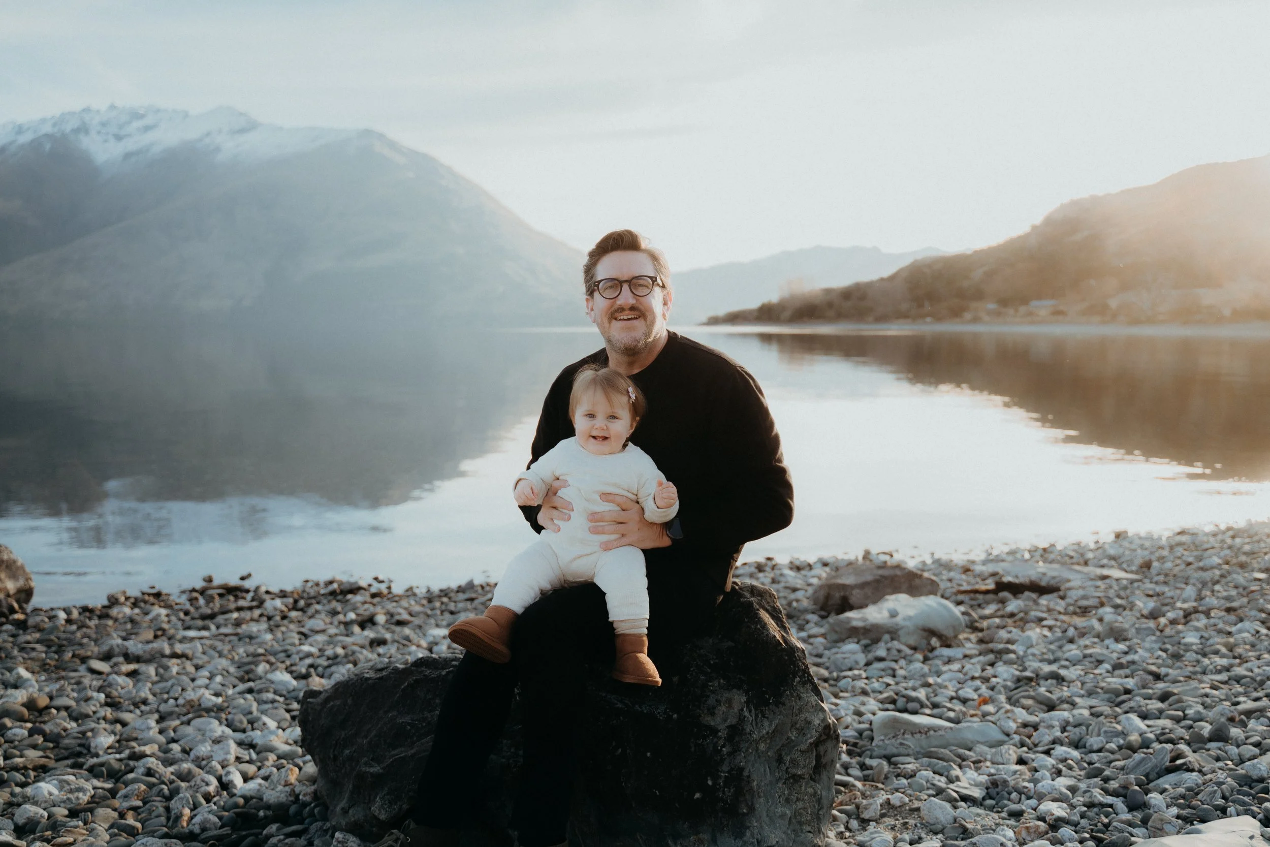 Father holding daughter while sitting on a rock at homestead bay