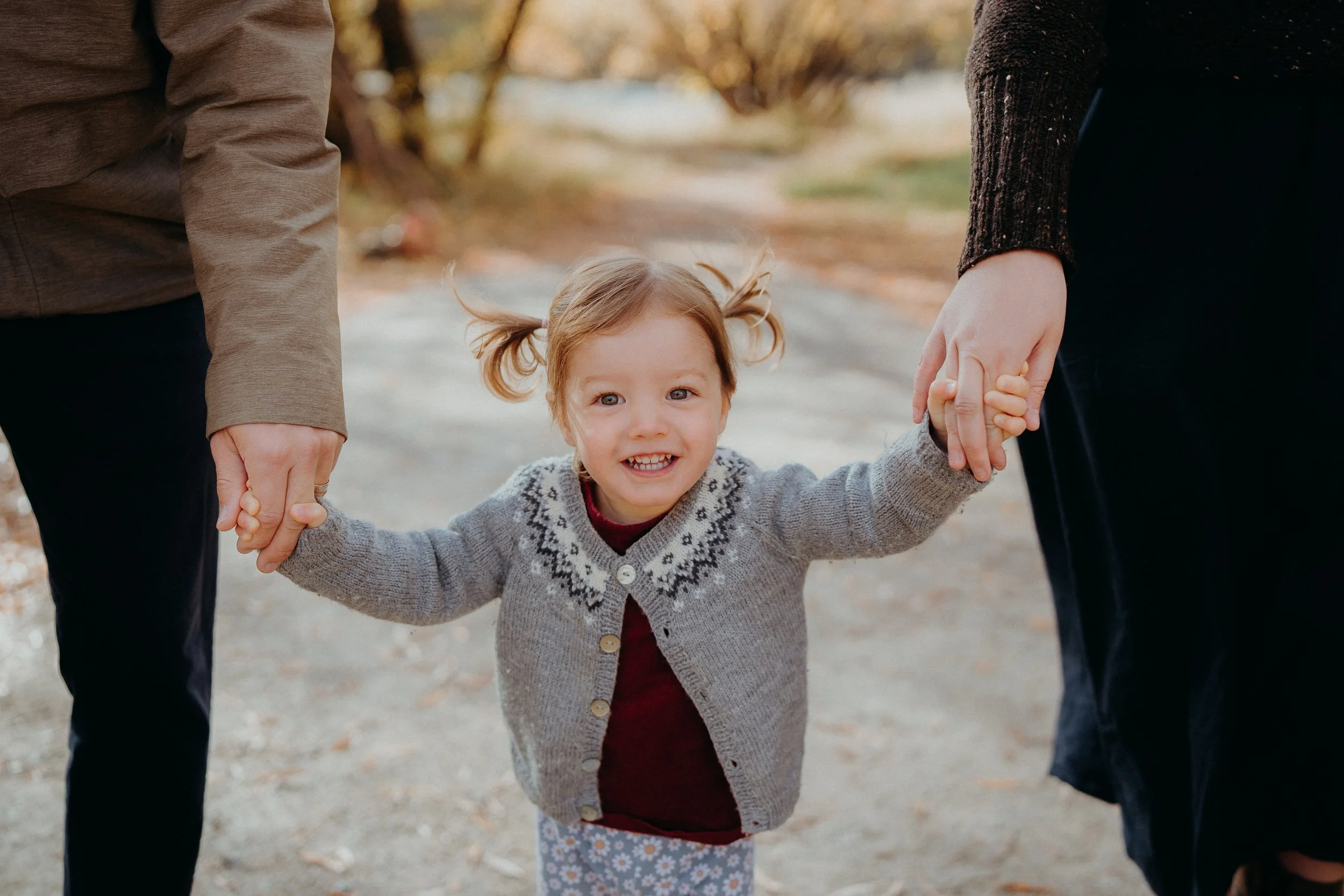 Small child standing between both parents holding hands
