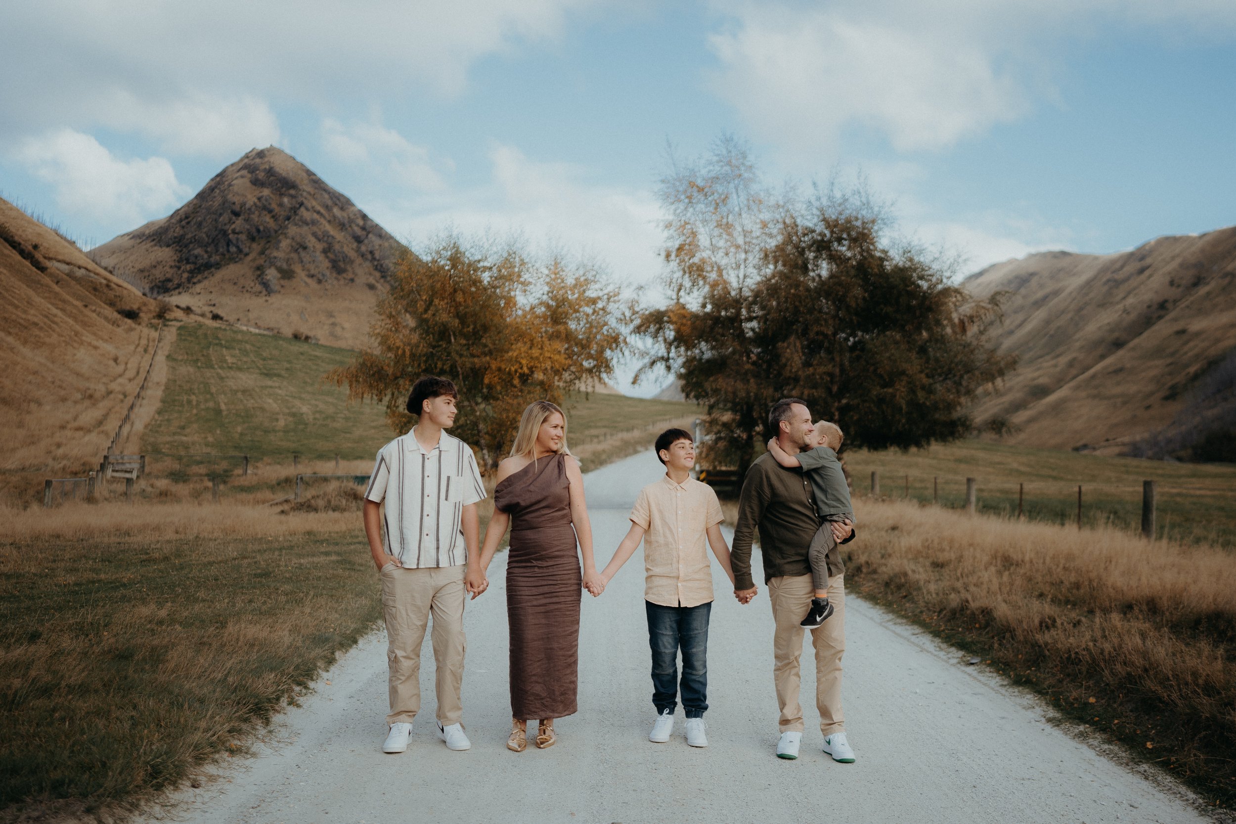 Family holding hands standing in middle of road at moke lake with mountains in background