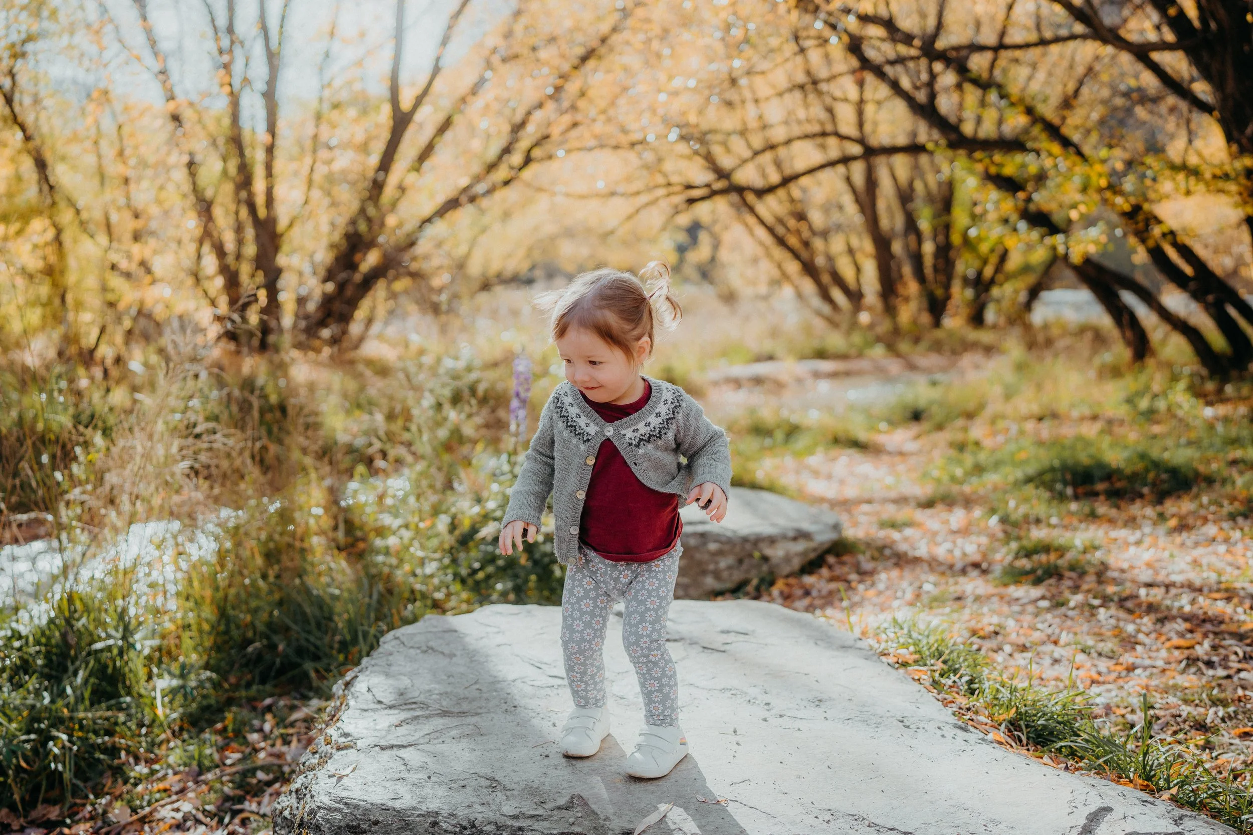 Small child playing on rock beside Arrowtown stream