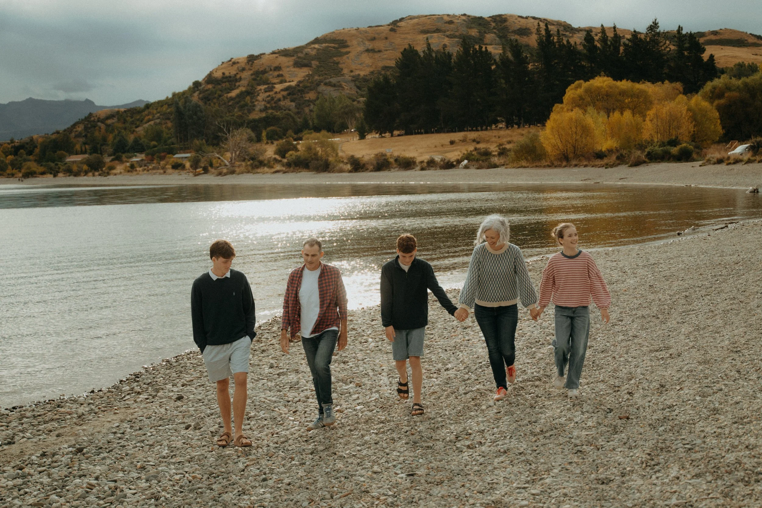 Family of 5 holding hands walking along Jacks point beach in Autumn